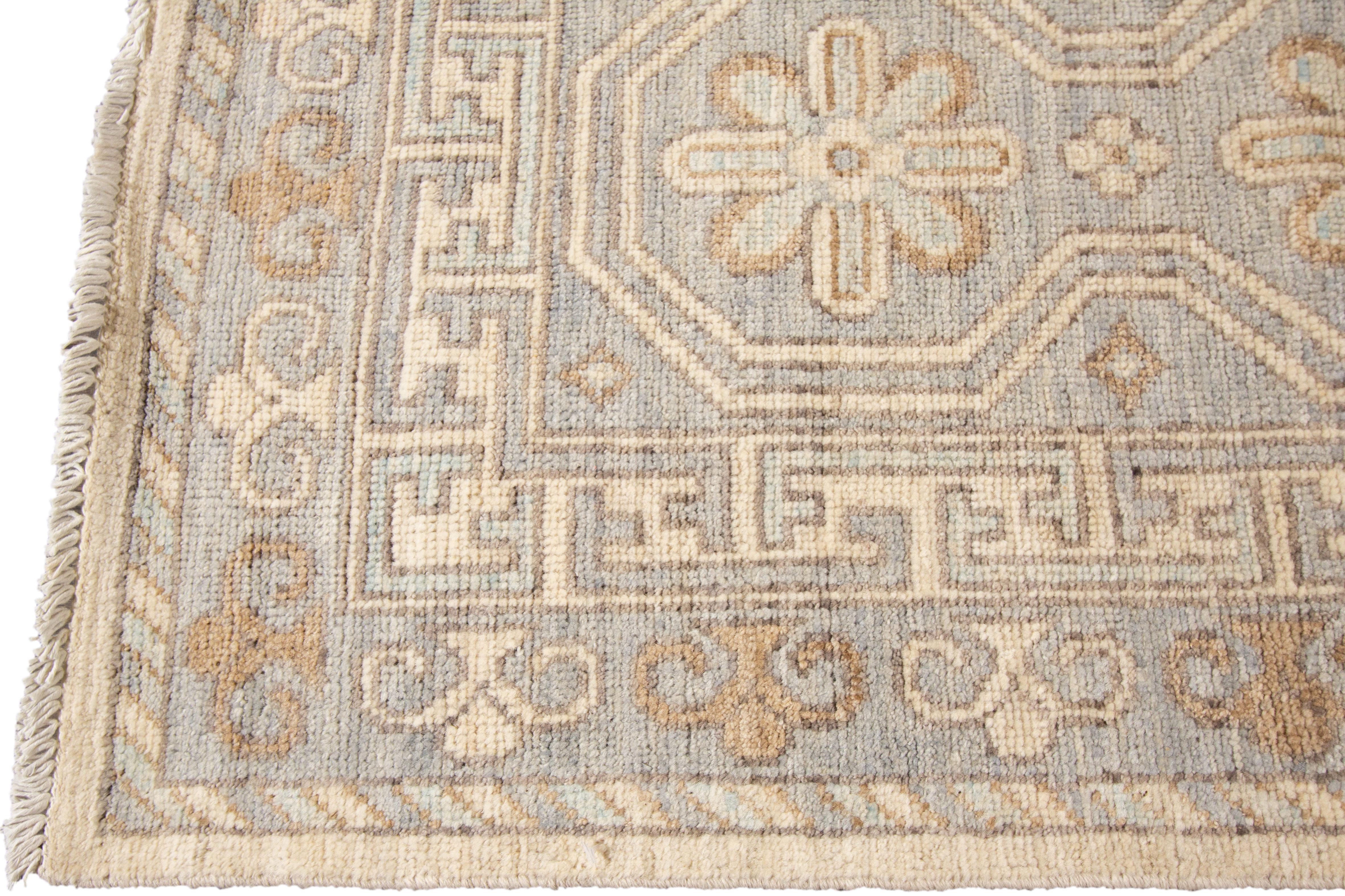 A 21st century modern hand knotted Khotan-style rug with an ivory field and multi-medallion design. This rug measures 12'2