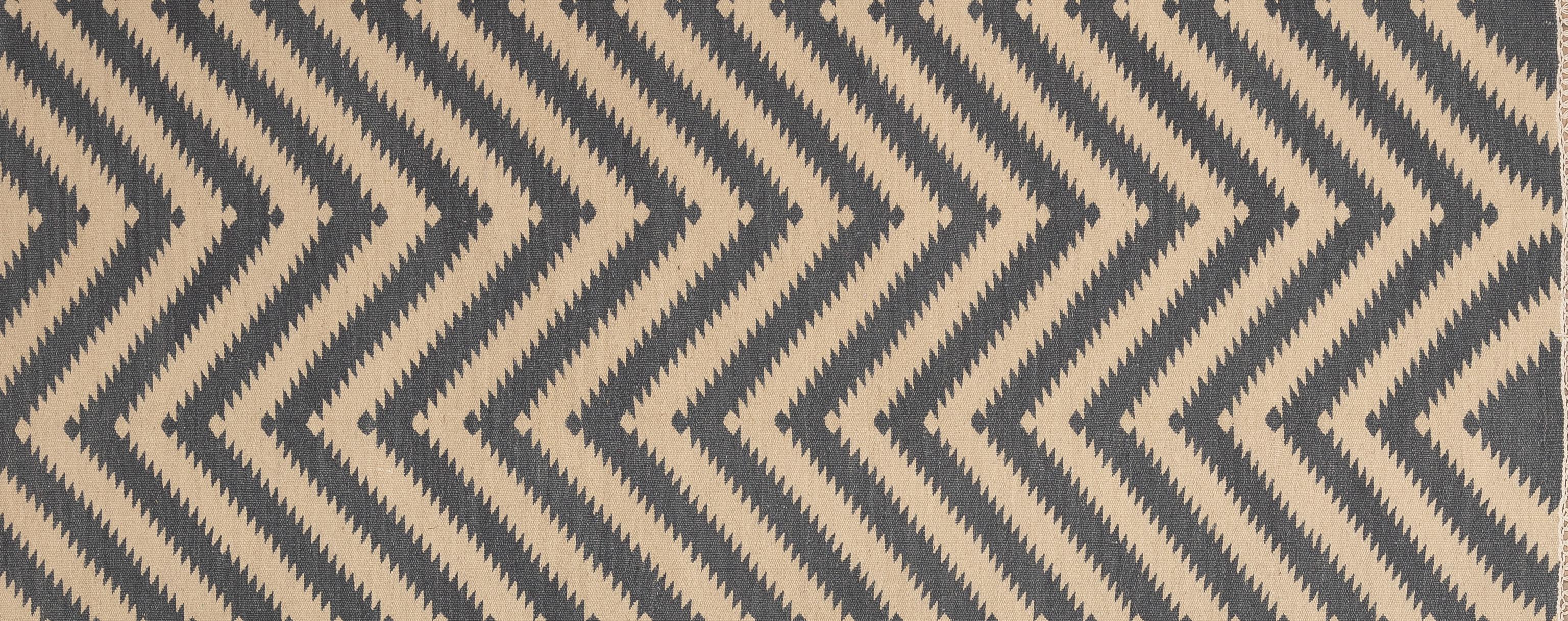 Questo divertente e unico tappeto a trama piatta è noto come Rug & Kilim. È stato tessuto a mano su una base di legno in India. Il motivo a zig-zag si ripete da un bordo all'altro. Porta la vivacità nel tuo spazio con questo pezzo moderno.