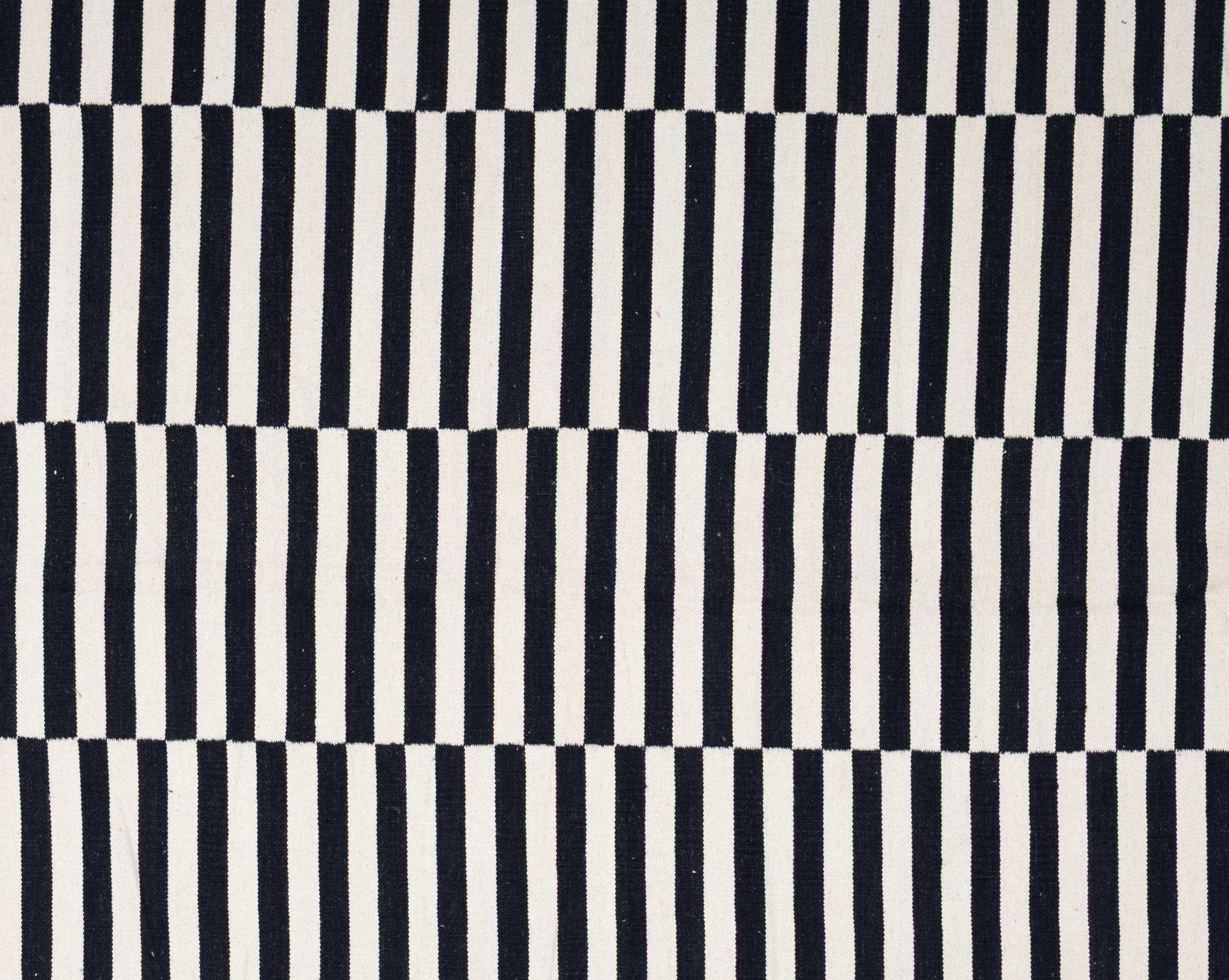 Questo tappeto kilim moderno, audace, tessuto in piano ed elegante, offre una prospettiva nuova a una tradizione di tessitura antica. Realizzato a mano con lana al 100%, il tappeto presenta una struttura leggera e di basso profilo, con la geometria