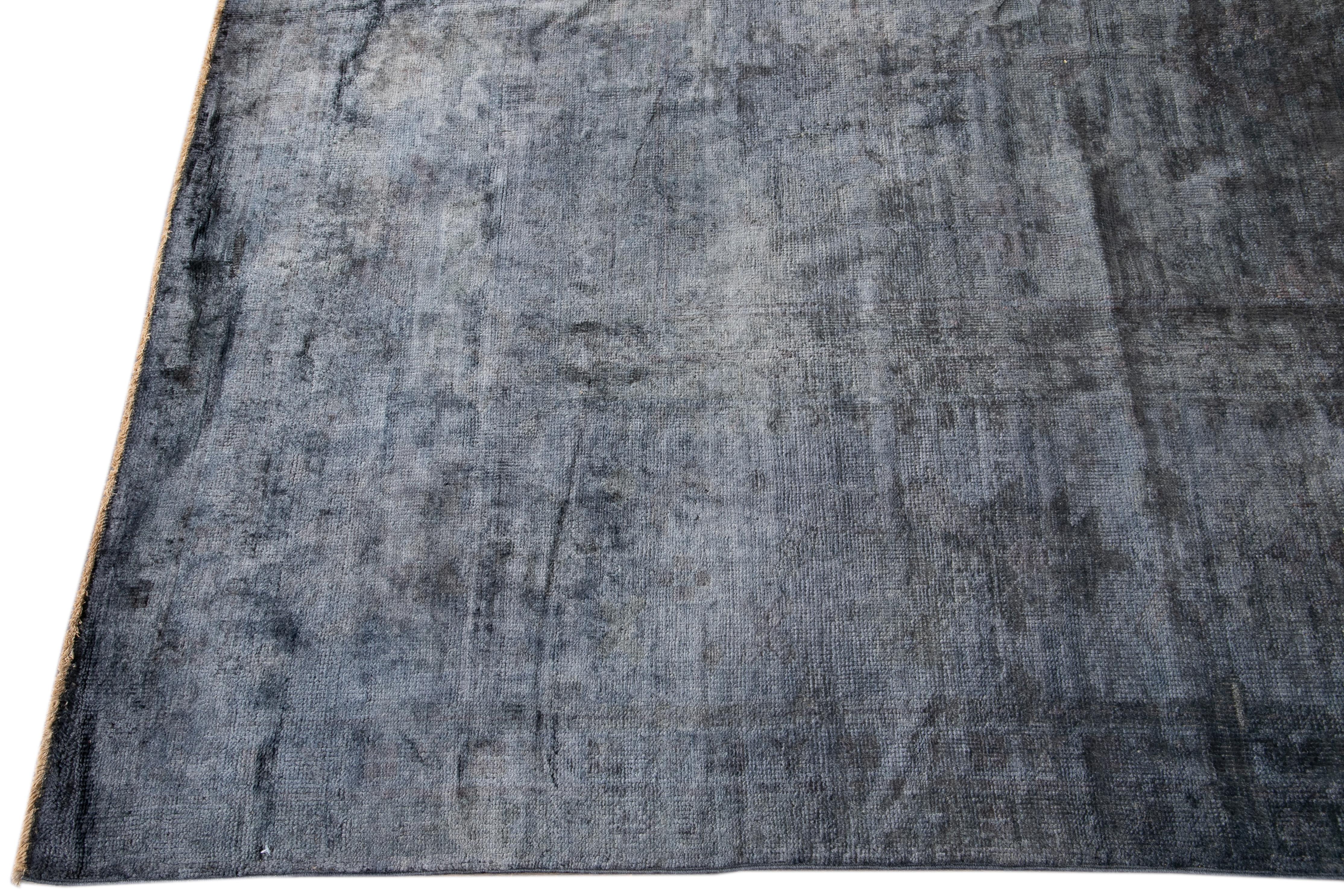 Beautiful contemporary overdyed rug, hand knotted wool with a blue field, silver accents, and a subtle center medallion design.
This rug measures 13' 2