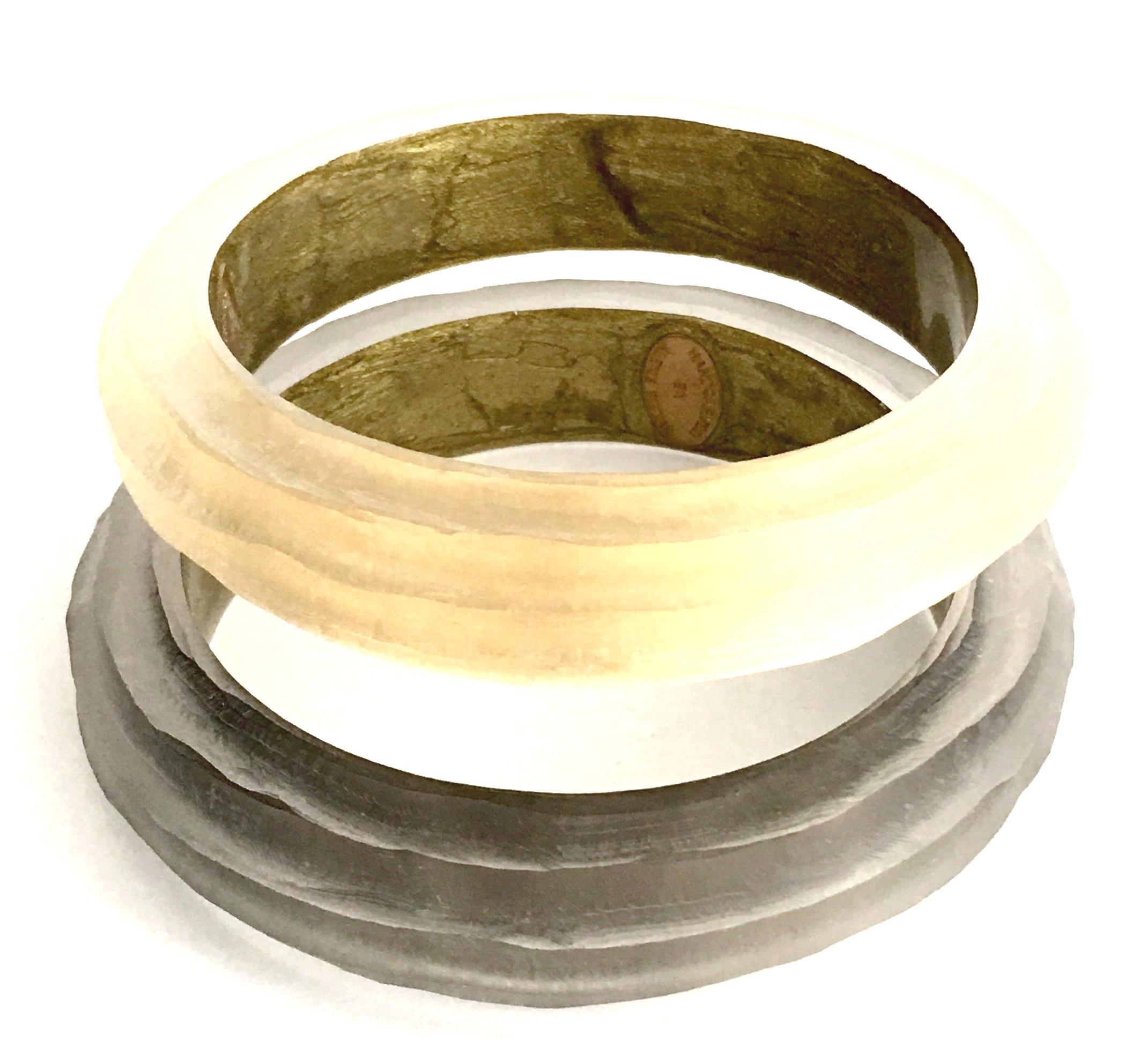 21st Century Modern Pair Of Hand Carved Lucite Bangle Bracelets By, Alexis Bittar. This identical pair of two different colored bracelets feature the iconic Alexis Bittar frosted hand carved Lucite, one of a champagne hue the other a smoky charcoal.