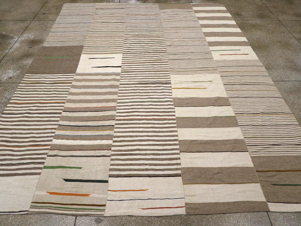Esta alfombra persa Kilim de tejido plano del siglo XXI, que mide 3 m x 5 m, presenta un diseño bellamente estructurado pero fluido, compuesto por paneles verticales. Cada panel muestra una disposición única de rayas horizontales de anchura