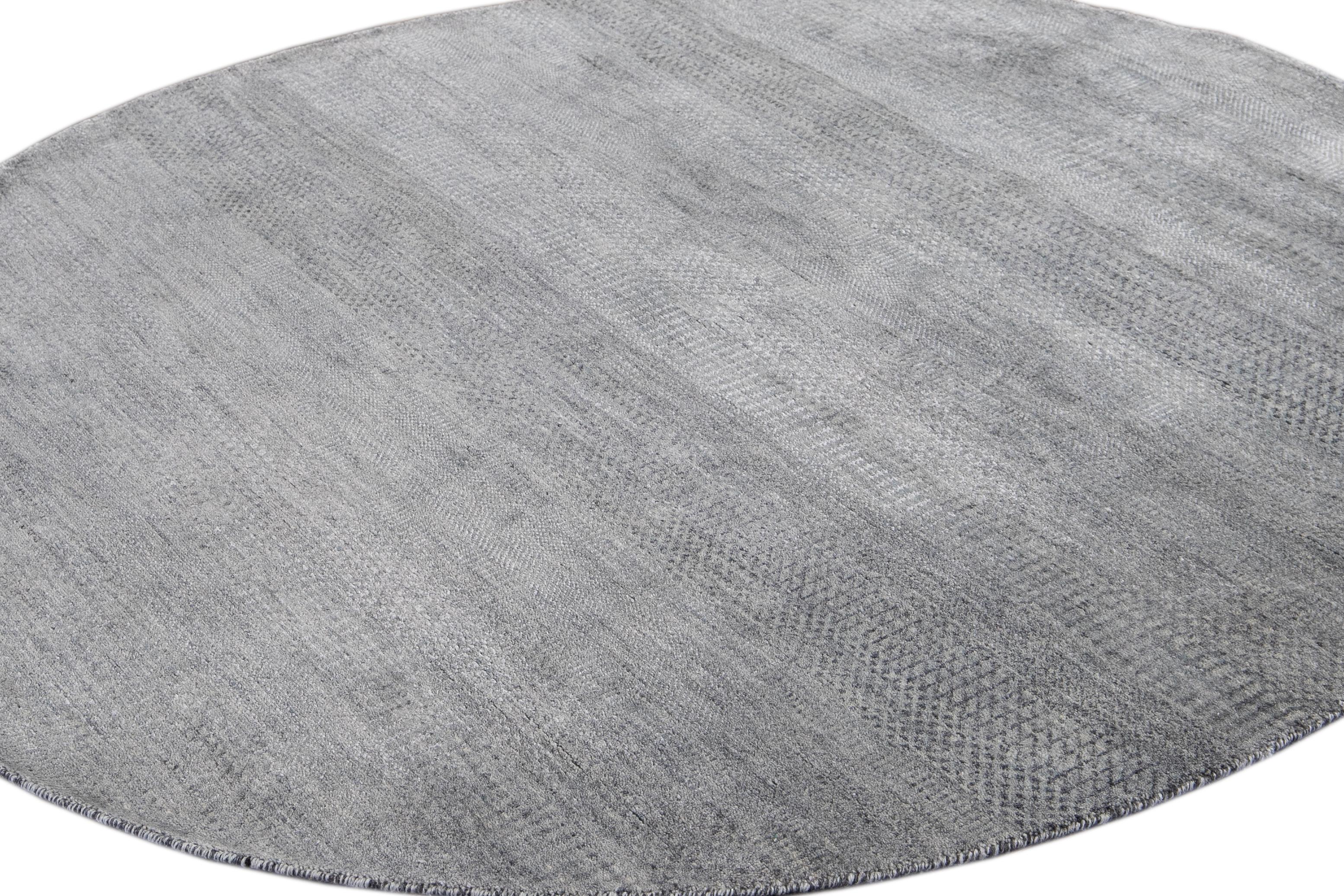Beautiful contemporary Savannah round rug, hand knotted wool with a gray field, silver accents in an all-over striped design, circa 2019.
This rug has a diameter of 6' 0