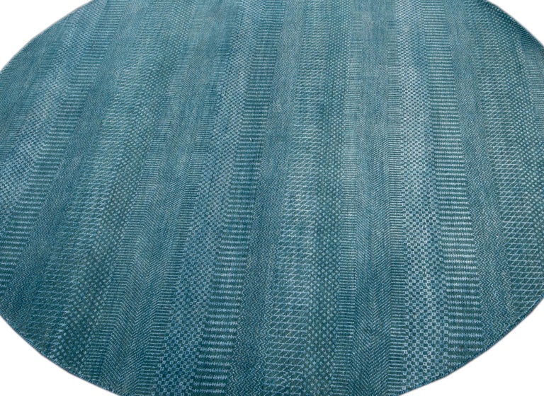 Beautiful contemporary Savannah round rug, hand knotted wool with a teal blue field in an all-over striped design.
This rug has a diameter of 6' 1