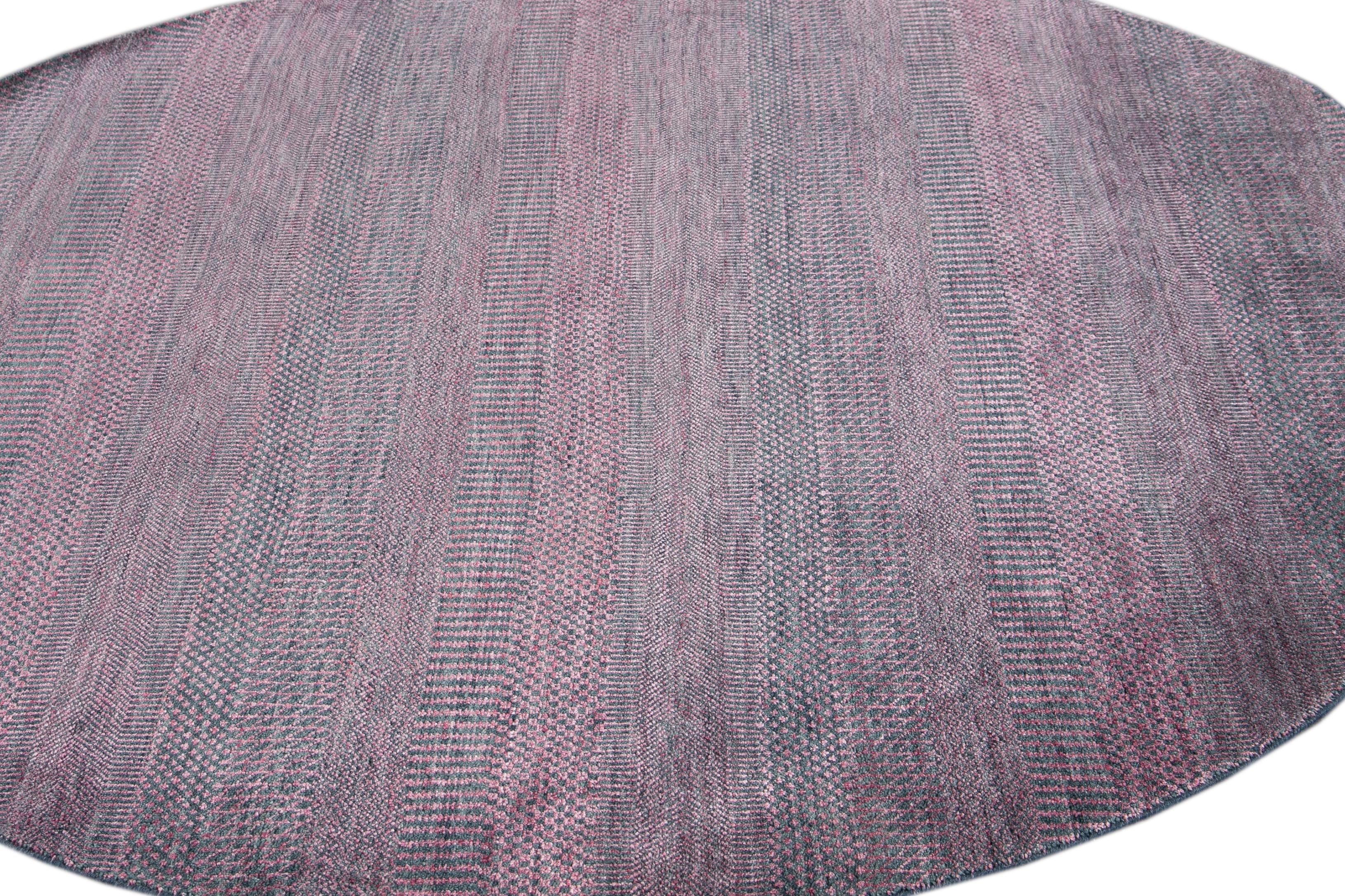 Magnifique tapis rond contemporain Savannah, en laine nouée à la main avec un champ rose, des accents bleus dans un design rayé all-over.
Ce tapis a un diamètre de 7' 0