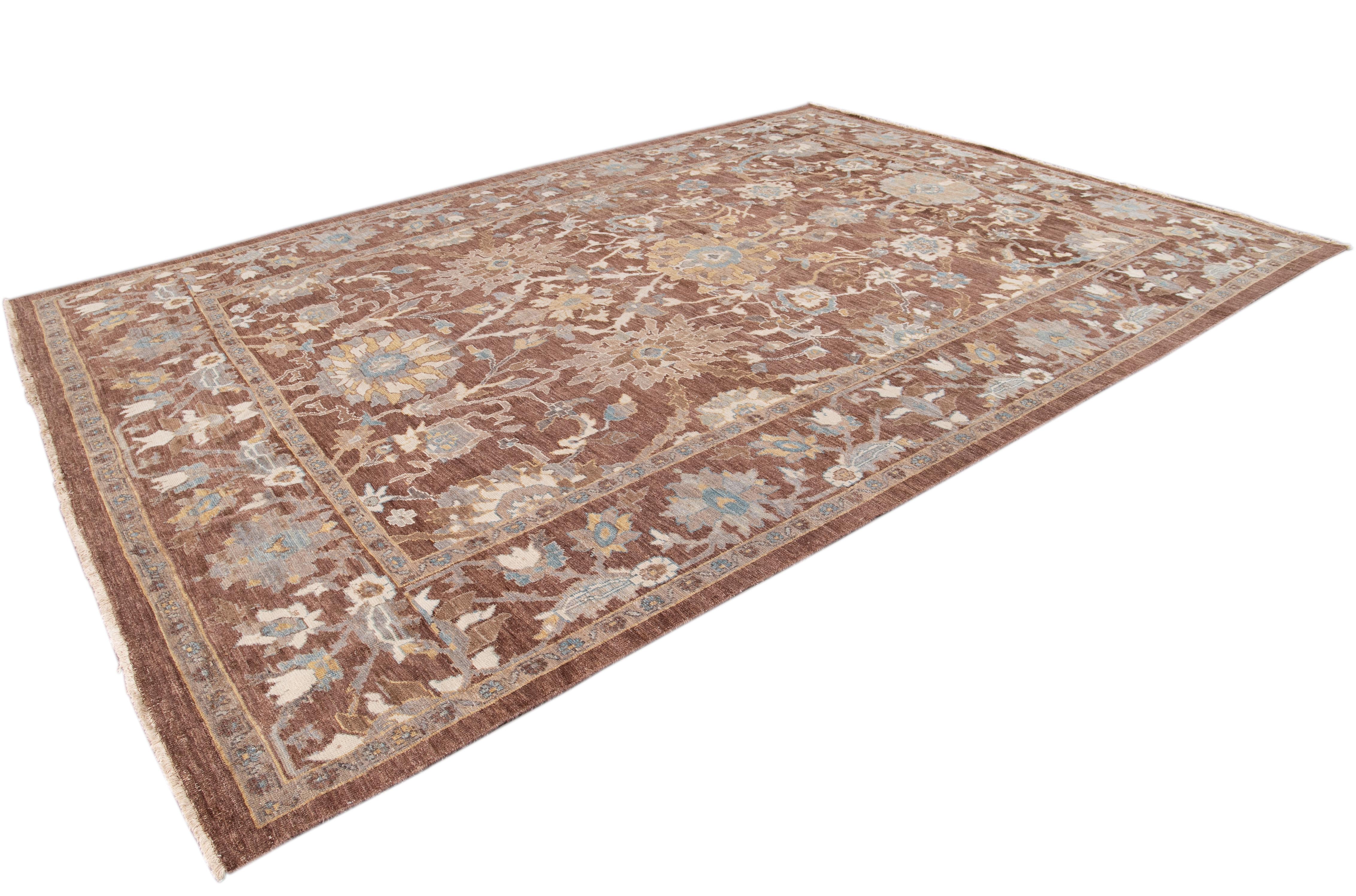 Beautiful 21st century contemporary Persian Sultanabad rug, with a brown field, ivory, tan and blue accents in an all-over floral design.
This rug measures 9' 10
