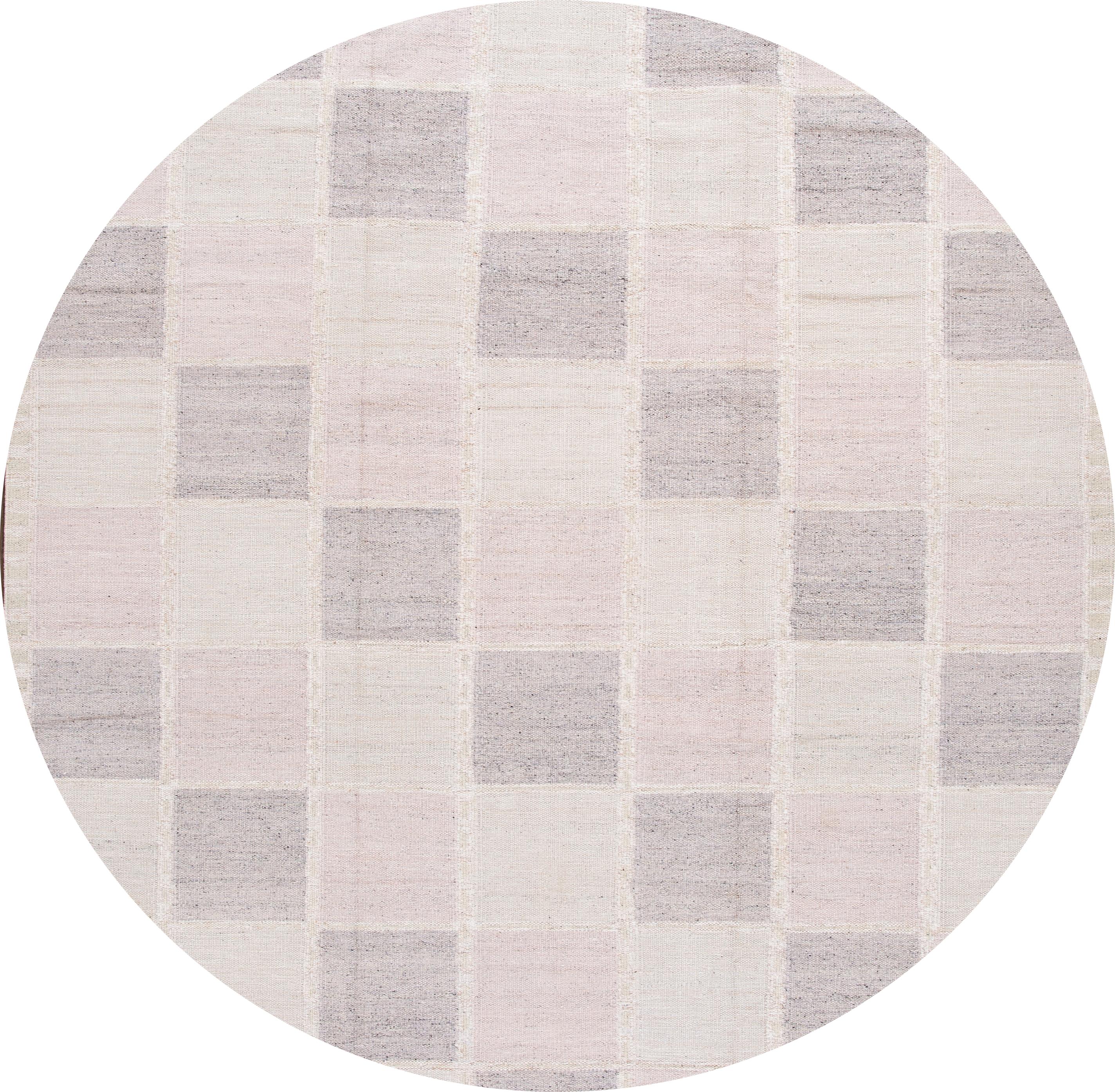 Beautiful 21st century modern Swedish hand knotted wool rug with a beige field, pink, and gray accents in an all-over checks design

This rug measures: 9'1