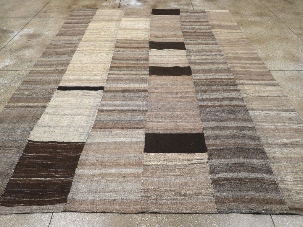 Esta alfombra turca Flatweave Kilim del siglo XXI, que mide 3,8 m x 4,8 m, presenta una composición de patchwork bellamente estructurada que pone de relieve el arte de las técnicas de tejido tradicionales. El diseño mezcla bandas horizontales de