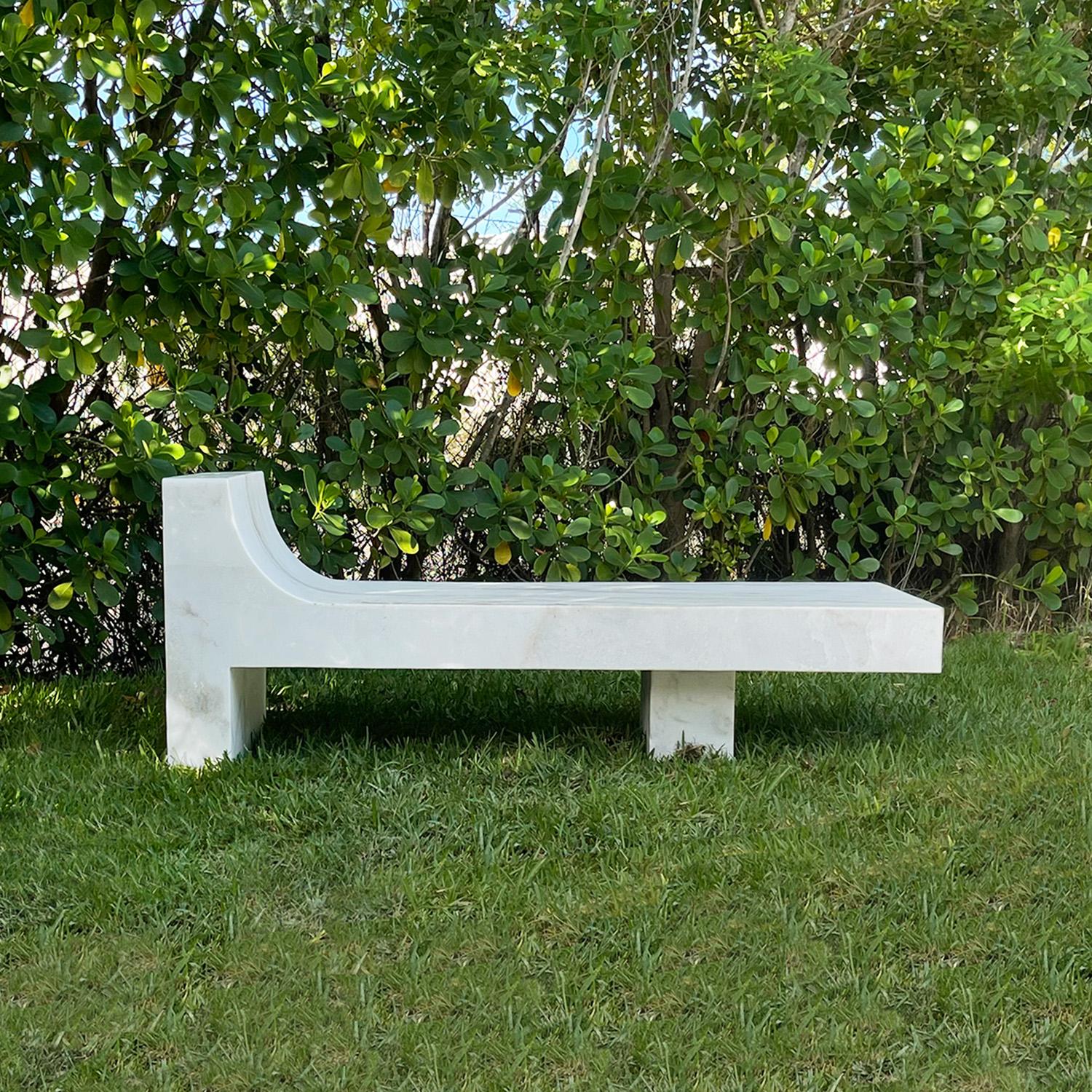 Ce banc de jardin au design unique est sculpté à la main dans un seul bloc de marbre blanc avec de fines veines grises. L'extraordinaire design sculptural reflète le summum de la beauté intemporelle. Le dossier élégamment prolongé et la base