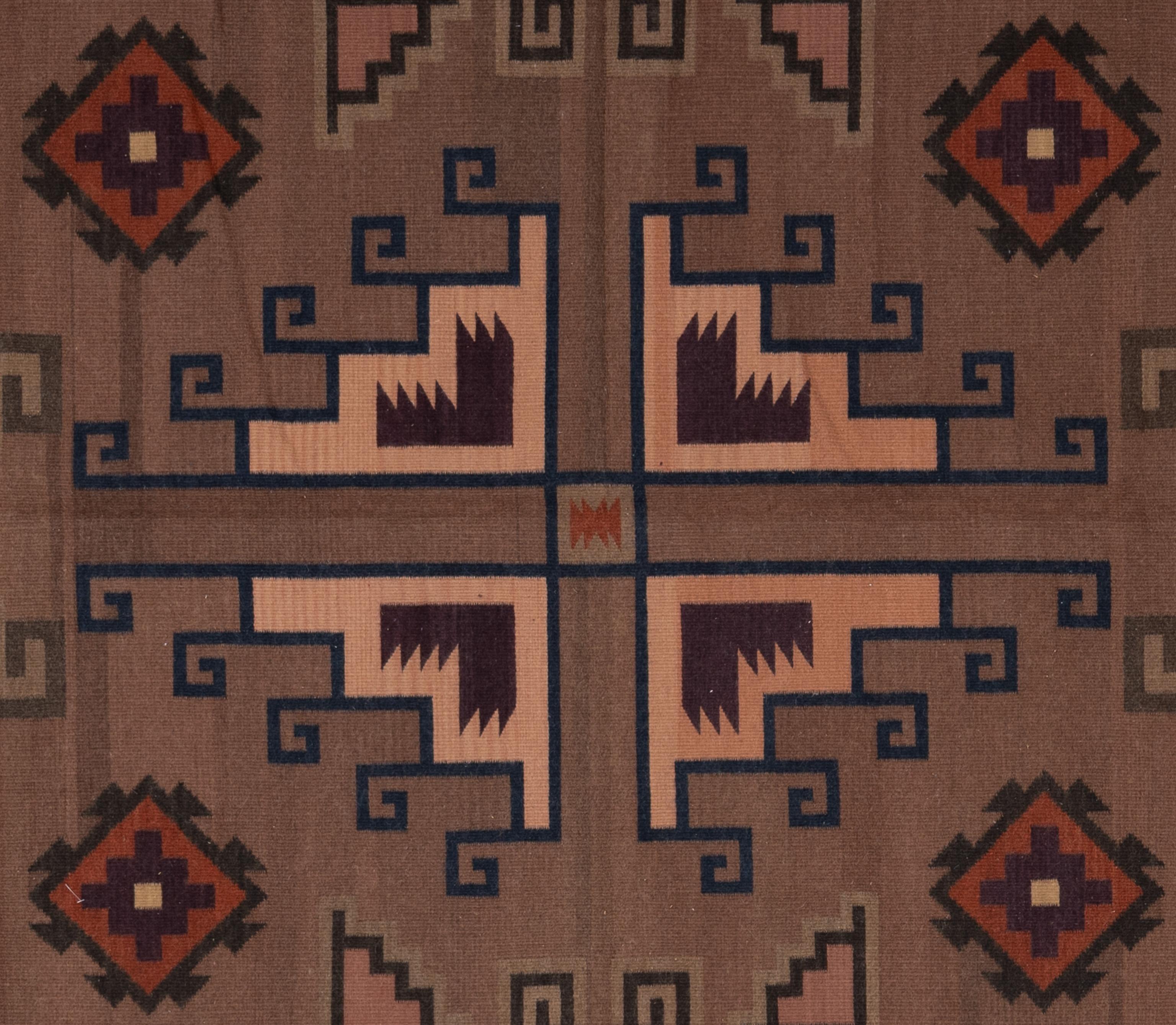 Ce tapis zapotèque tissé à la main au Mexique présente un motif tribal audacieux avec des tons rustiques rouges et mauves, accentués par des couleurs brunes profondes. Fabriqué en laine de haute qualité, ce tapis présente des motifs zapotèques