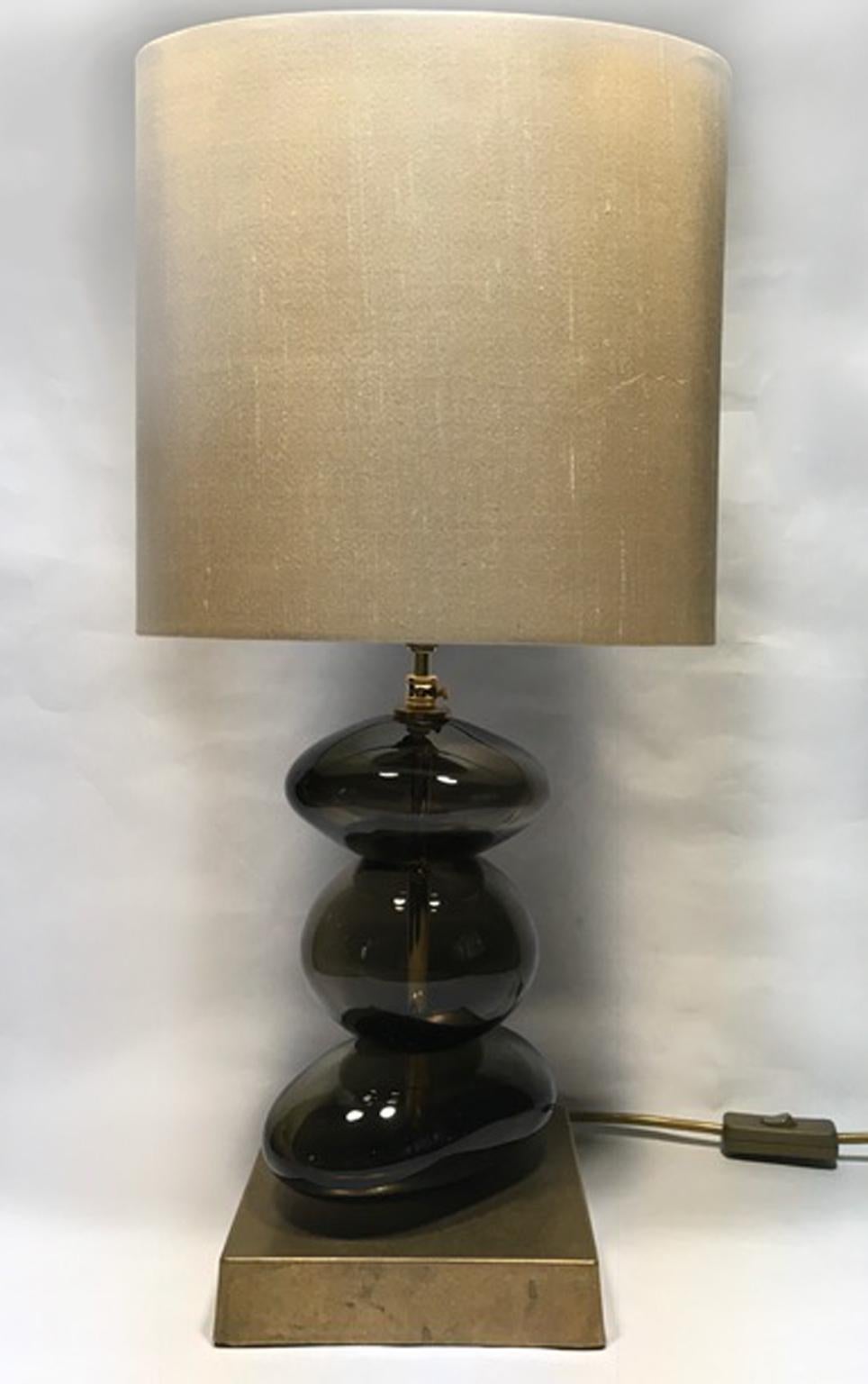 This is a pair of bronze color blown glass table lamps with pure silk hand made lampshades, of contemporary production.
It is a beautiful eye catching object, a piece of art for its elegant presence and for the organic shape of the handcrafted body