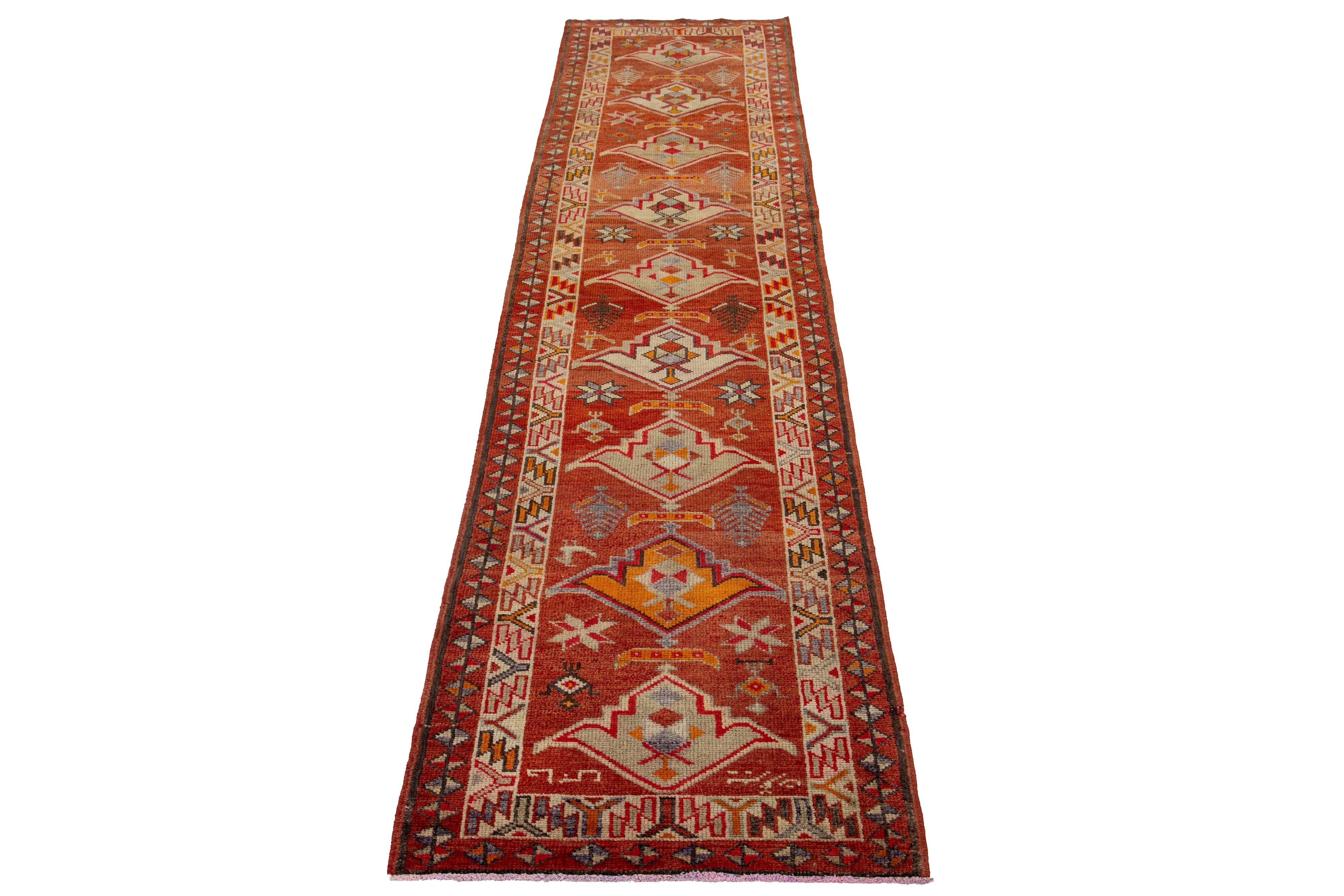 A beautiful modern Turkish runner featuring a red-rust field and a tribal geometric design that covers the entire rug, with accents in multiple colors.

This rug measures 2' 11