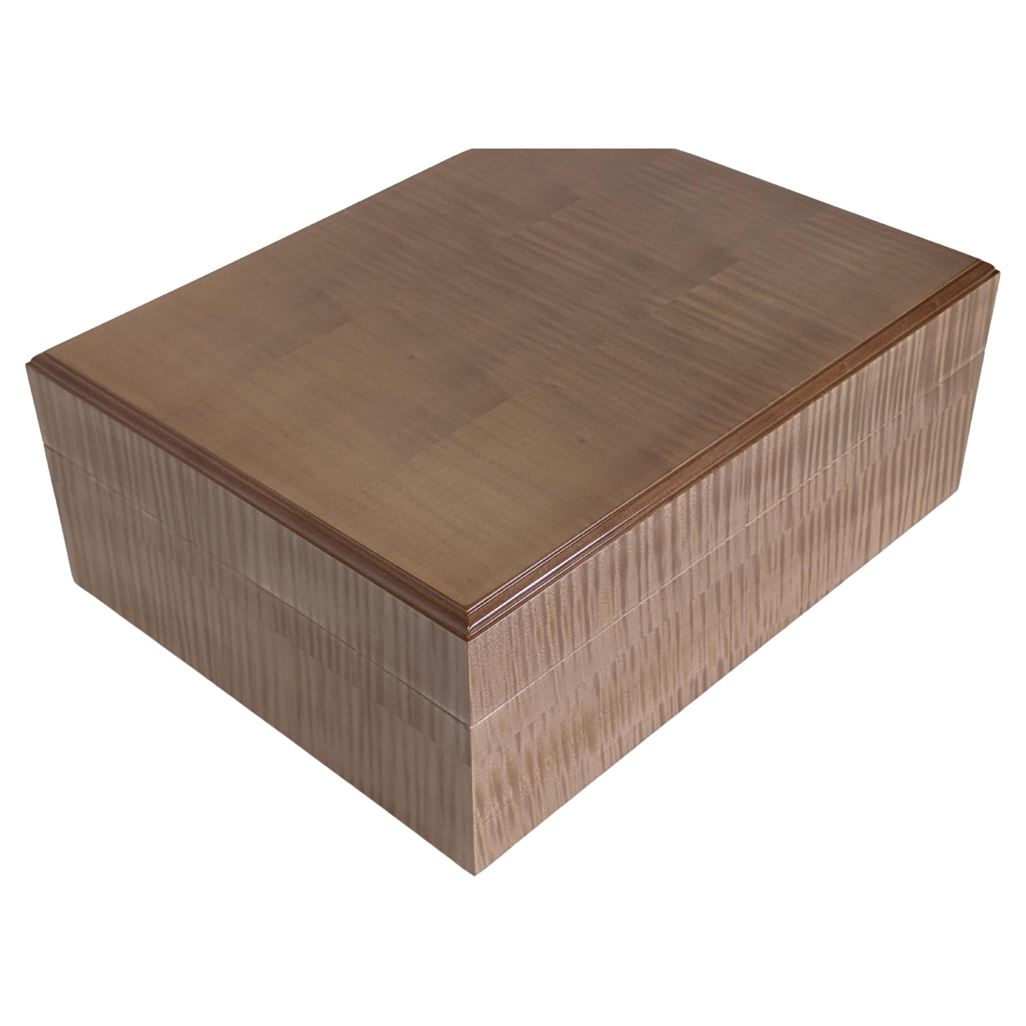 A luxurious humidor, hand made in selected ripple sycamore veneer. With solid sycamore edge mouldings, and sides. The outside of the box is finished in a full gloss, hand burnished lacquer, with a slight pink tint to the colour. The sycamore inside
