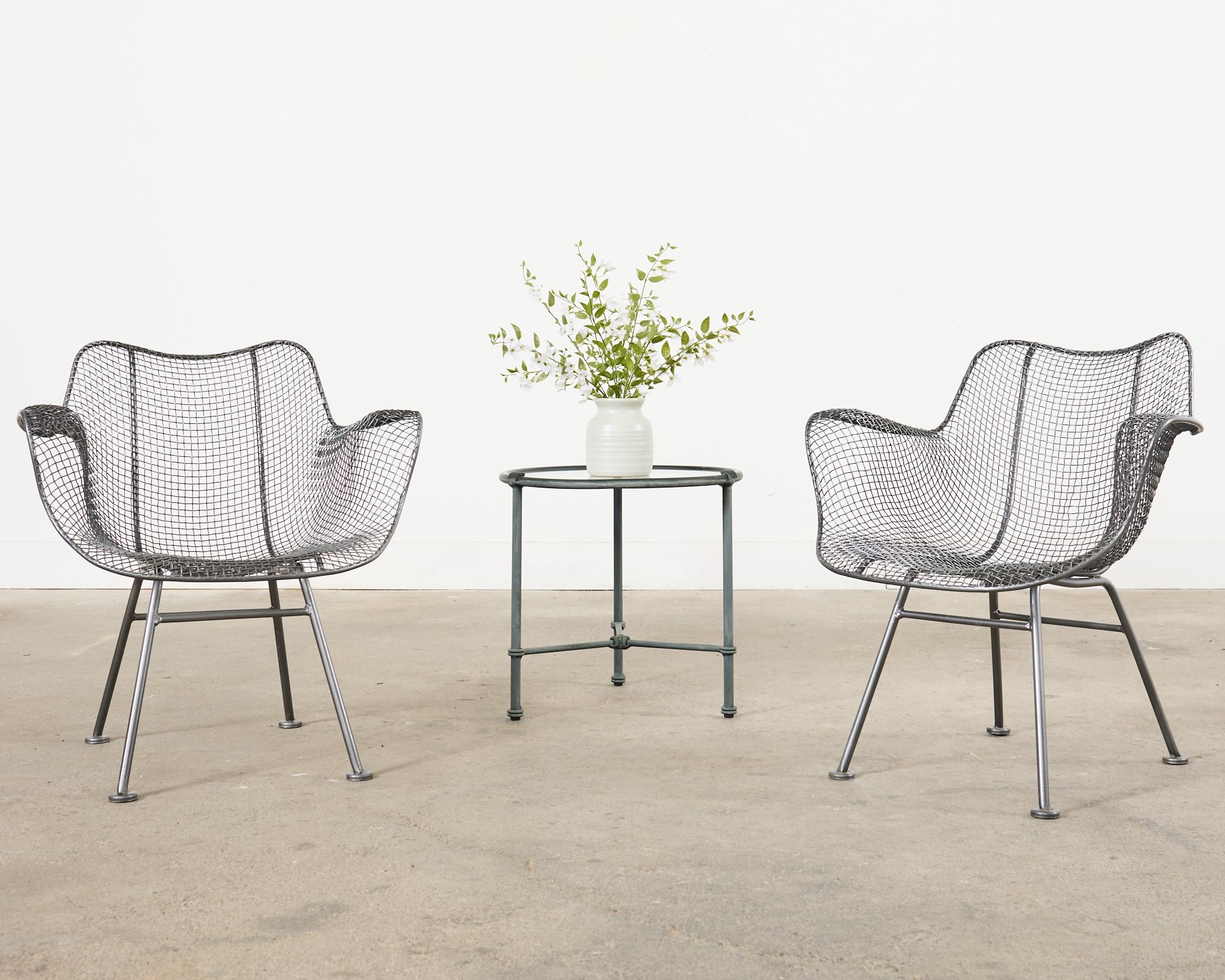 Icónico conjunto reeditado del siglo XXI de cuatro sillones de comedor Sculptura de alambre moldeado, de Woodard. Las sillas tienen un acabado gris brillante personalizado que resplandece y brilla. Cada silla tiene un cojín de asiento negro. Se
