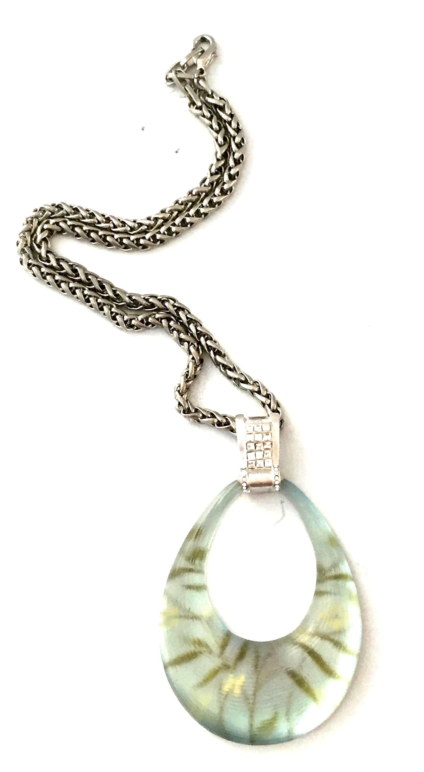 21st Century Modernist Brushed Silver, Swarovski Crystal & Lucite Pendant Necklace By, Alexis Bittar. Features a carved Lucite oval loop in mint green jungle print with brushed silver Swarovski crystal adorned bail and claw closure on a silver