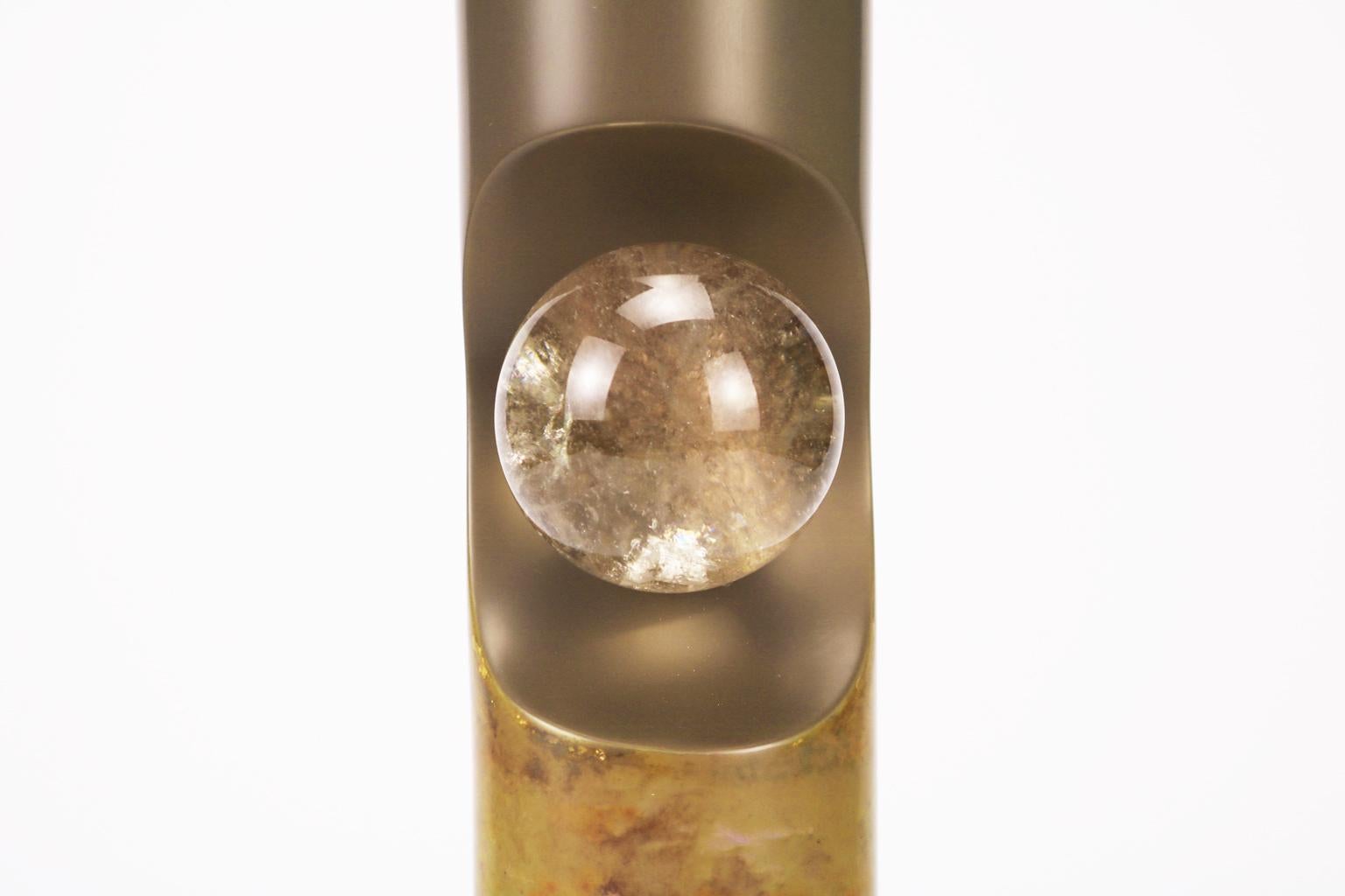 Rhapsodic vessel displaying an unconventional cylindrical design with an alcove housing an elegant smoky crystal sphere accent by Golem of Italy. The vessel has a suave charm due to the earthly colored lacquer tone and the lower part abstract