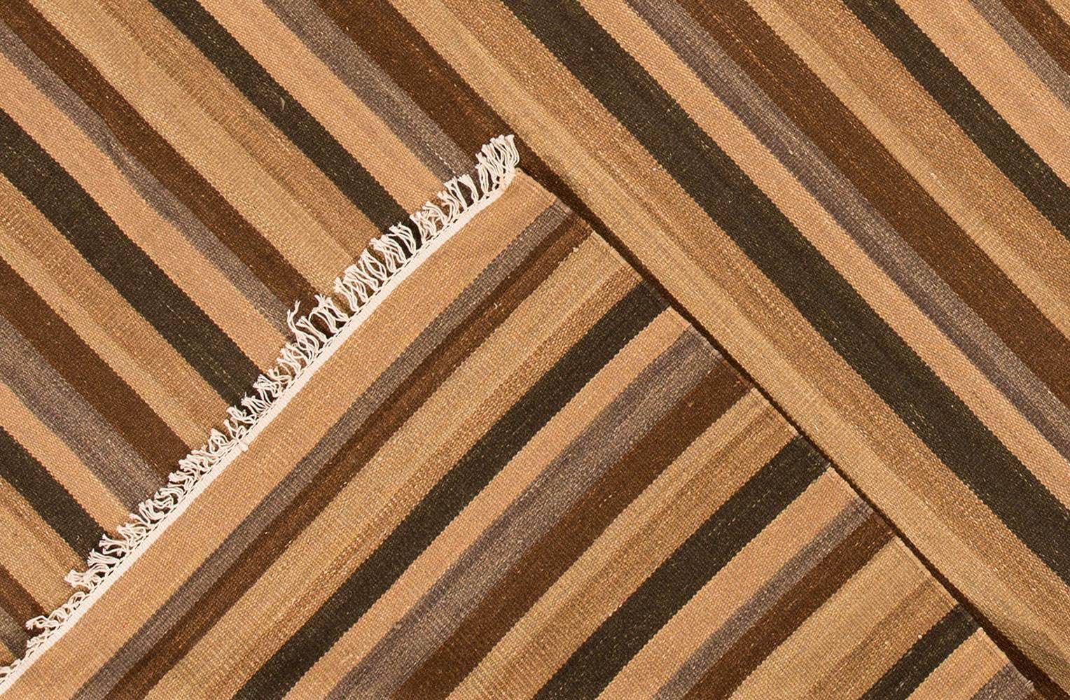 türkischer Kelim-Teppich des 21. Jahrhunderts. Dieses Stück zeigt ein gestreiftes Feld in Braun- und Erdtönen. Hat einen sichtbaren Saum. Maße 7,11 x 10,03.