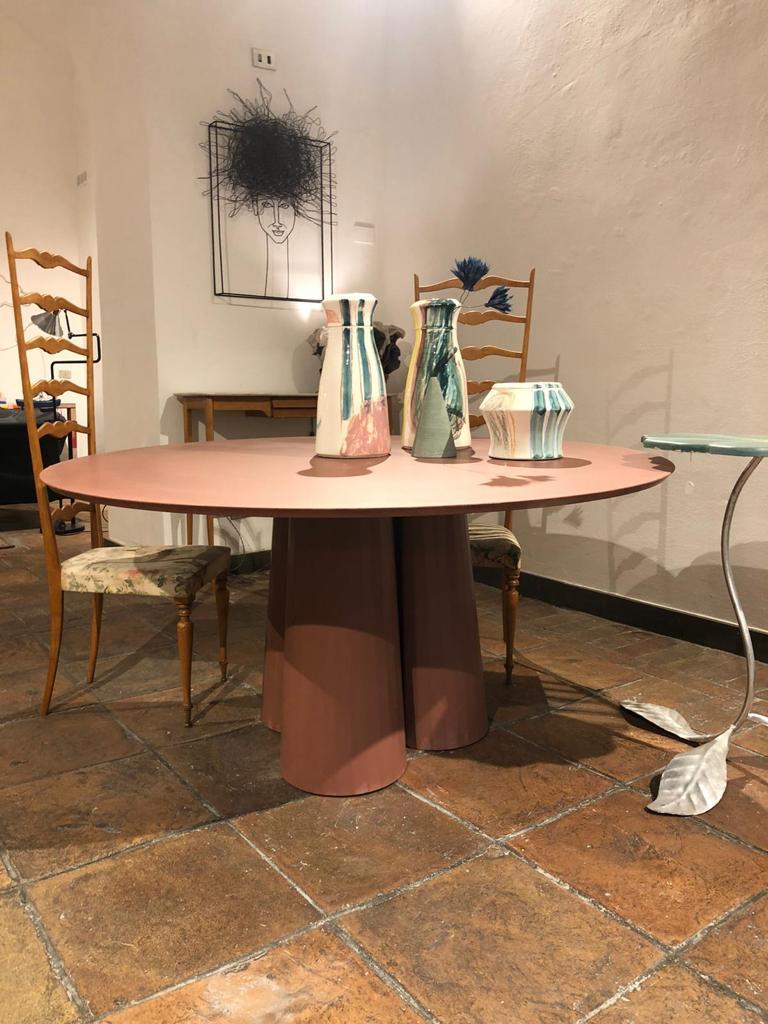 Rounded shape dining table part of a collection of modular system in ultra-high performing cement mortar. UHPC tabletop and base colored in the mixture and sandblasted. Available in eight different colors: Brick, silver, powder, cream, fir, dark,