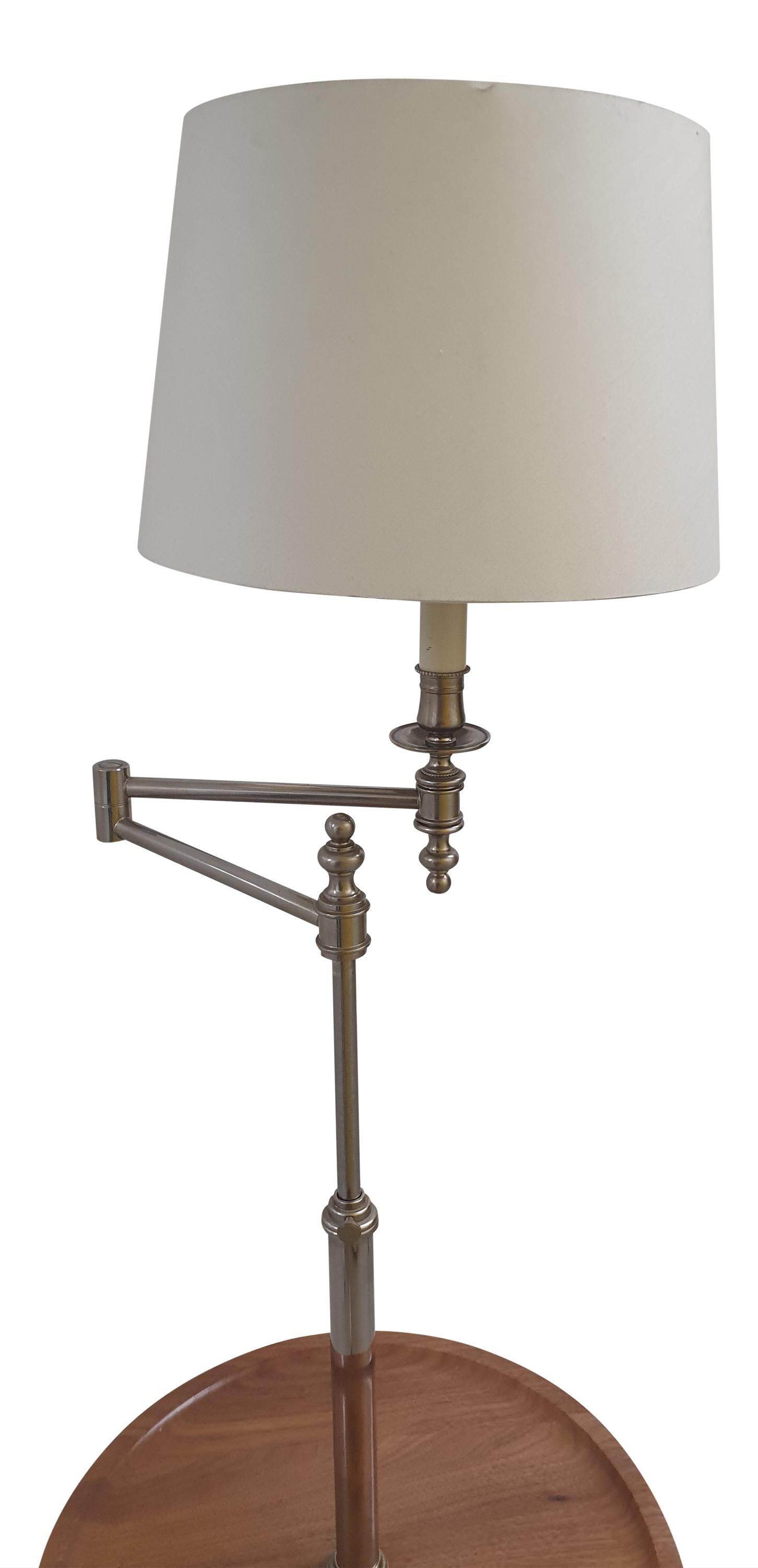 This is a rare LINLEY London swing arm floor lamp from the early noughties. Made from solid cast brass with a spun brass weighted base in Polished Nickel with a LINLEY stamped solid carved American Walnut floating table

The swing arm top is fully