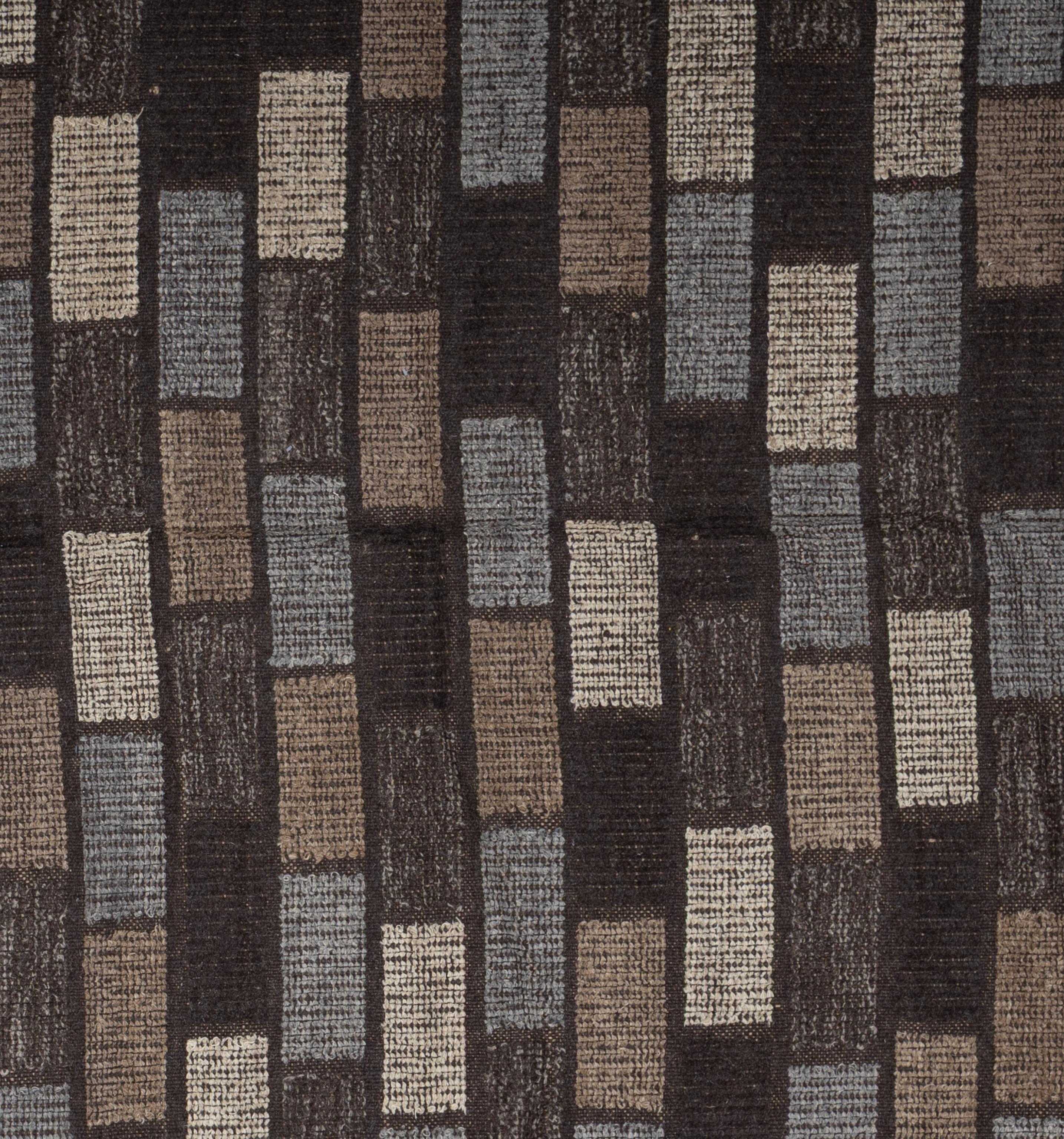 Ce tapis tout en laine présente une palette de tons joliment vieillis, avec des nuances douces de taupe, d'argile et de chocolat, offrant une élégance discrète à la fois classique et contemporaine. La texture est douce sous le pied et le design -