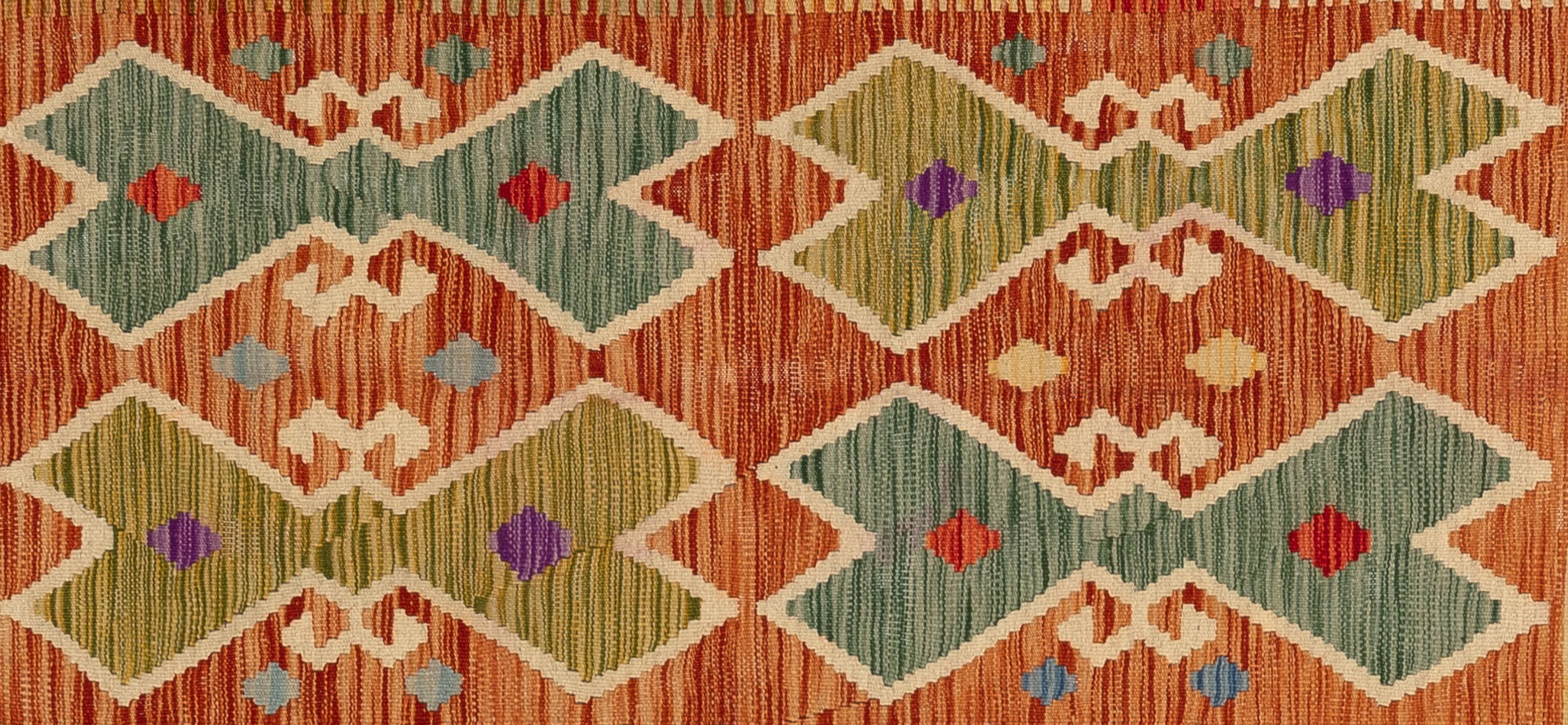 Dieser handgefertigte türkische Teppich im Flachgewebe-Stil besteht aus Wolle auf einer Wollunterlage. Sein variierendes, sich wiederholendes quadratisches Muster zeigt ein einzigartiges, farbenfrohes Design von Rand zu Rand. Dieser unvergleichliche