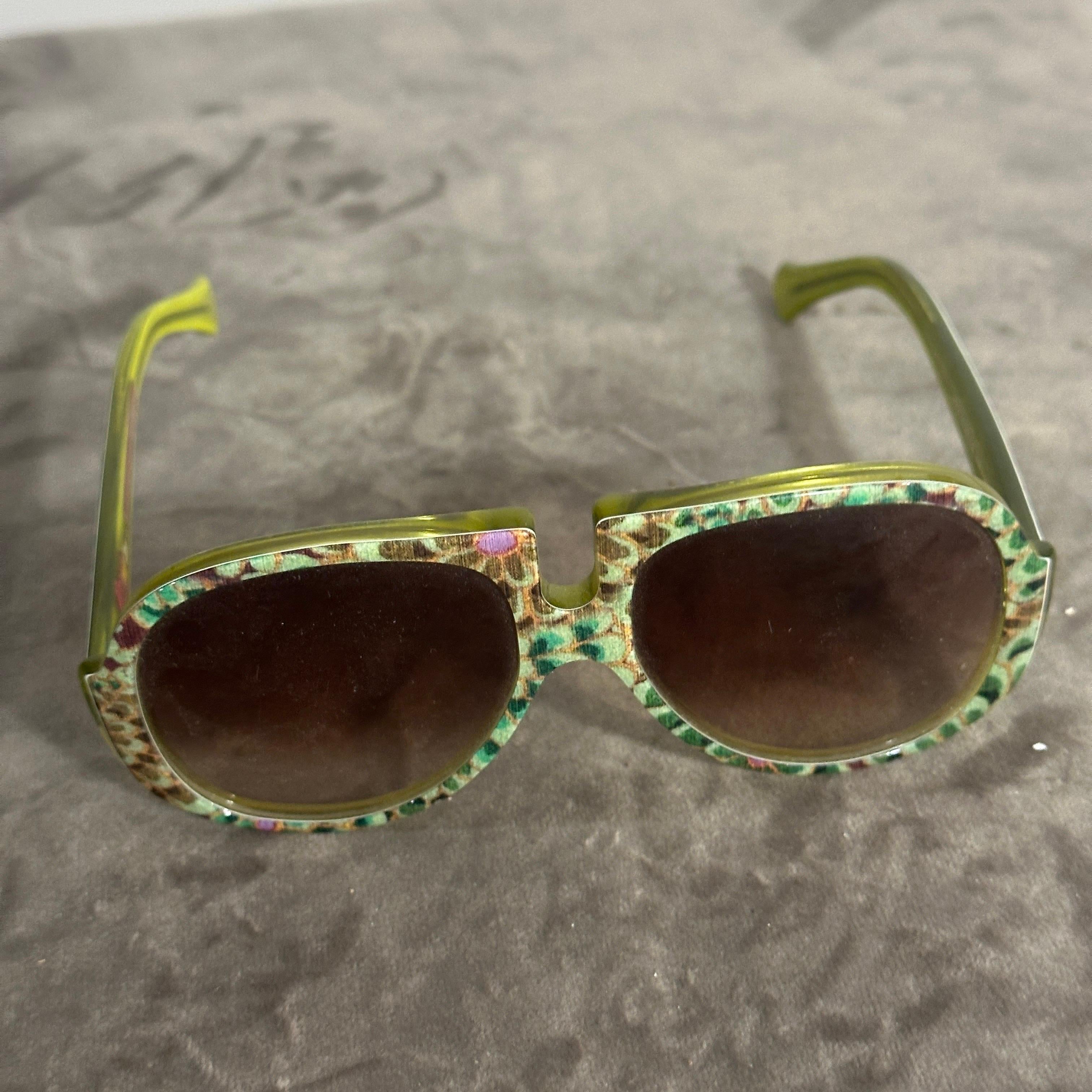 Es handelt sich um eine lila-weiße italienische Oversize-Sonnenbrille im Retro-Look von Patty Paillette, einer in Venedig ansässigen Designerin, die für ihre unverwechselbaren und gewagten Brillen bekannt ist.
Diese Kombination aus Farben und Stil