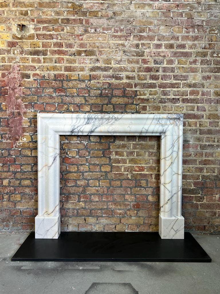 21st Century White Marble Breche Bolection Fireplace.
Hand Carved From Solid Block Breche Marble With A Nice White Background And Violet Veins Running Throughout. 
Although The Bolection Hand Carved Design Originated In The 16th Century, It Was More