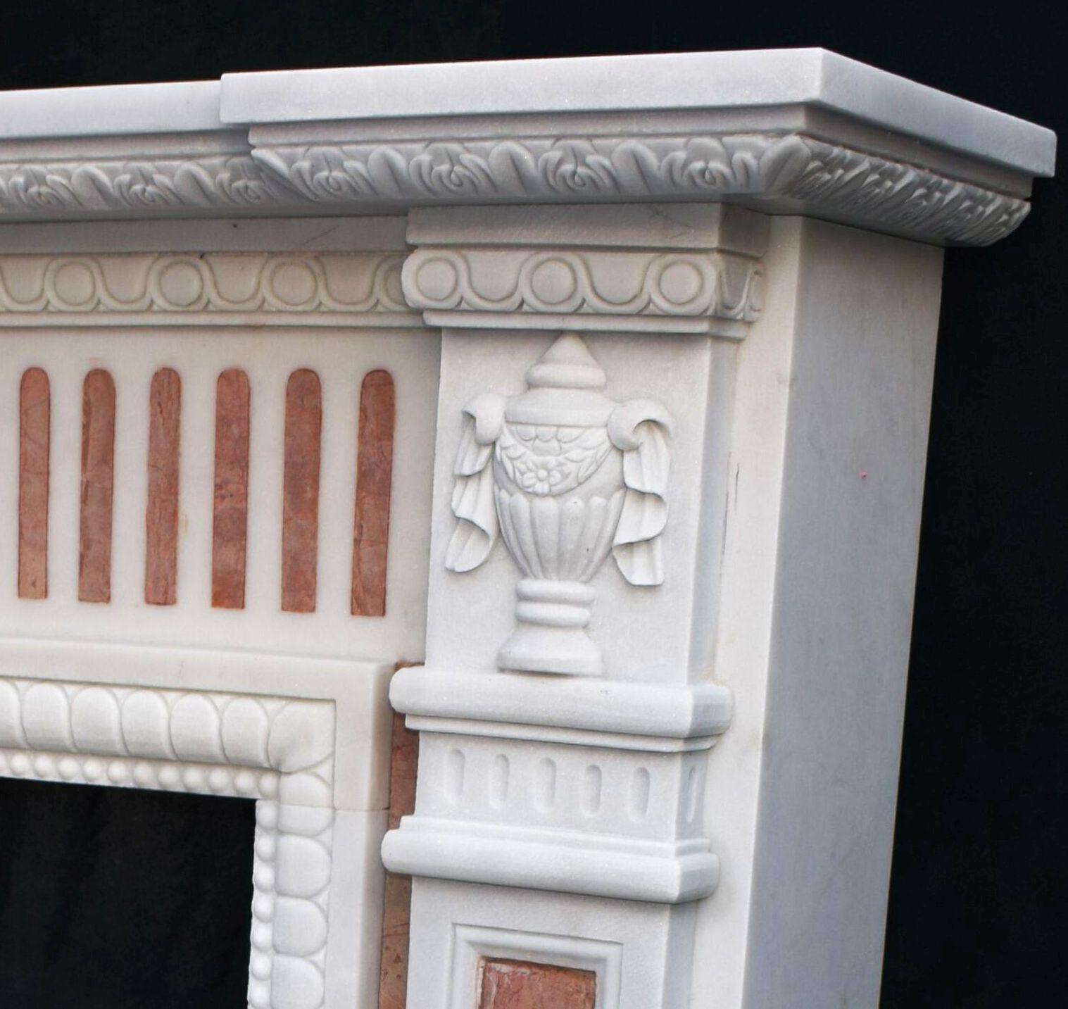 Une cheminée de qualité avec encadrement en marbre 
en marbre blanc sculpté avec des inserts en marbre rouge, la pièce étant taillée avec précision et très détaillée avec une sculpture en relief cannelée, des motifs d'urnes et des têtes de
