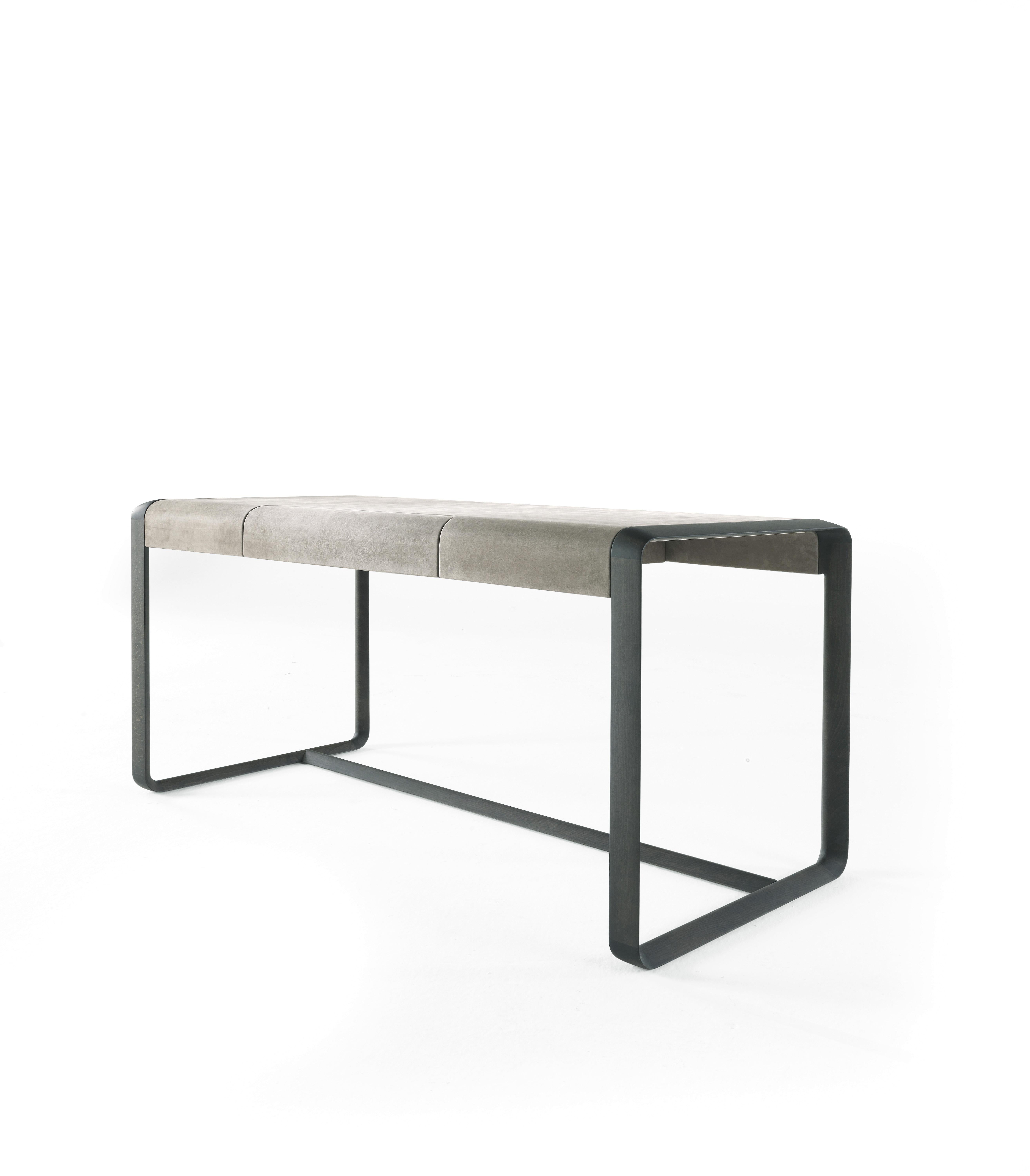 Elegant and functional, the Wynwood desk fascinates the viewer with its essential lines and refined charm. Made of solid beech wood dyed Smokey Grey, the desk is upholstered in soft nubuck for a comfortable and welcoming effect, while the slightly