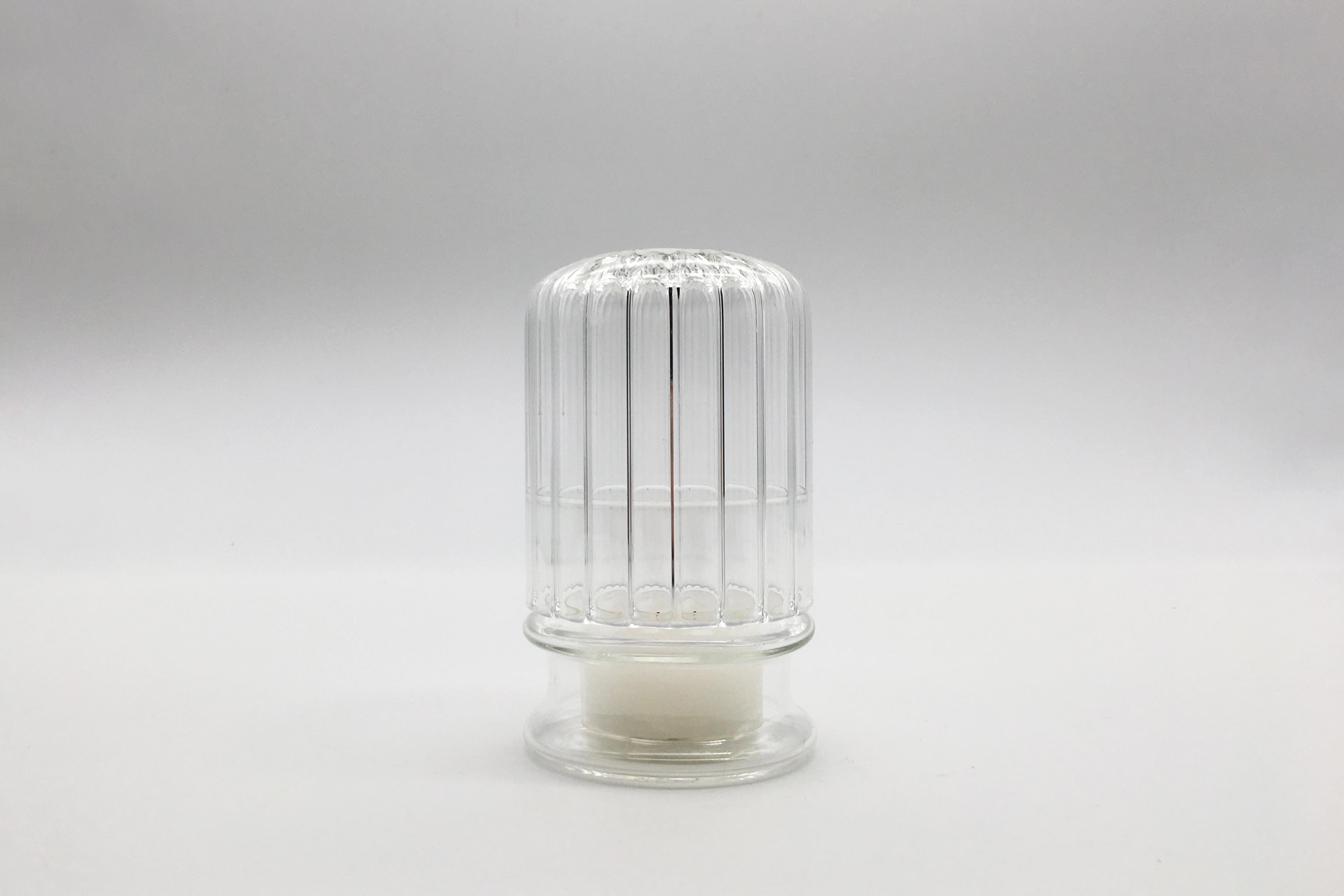 Moscardino ist ein eleganter, handgefertigter Kerzenhalter aus Borosilikatglas. Die Struktur dieses dekorativen Elements sieht aus wie eine Kuppel, die eine kleine Kerze schützt und beherbergt. Das schwache Licht des Kerzenfeuers schafft eine