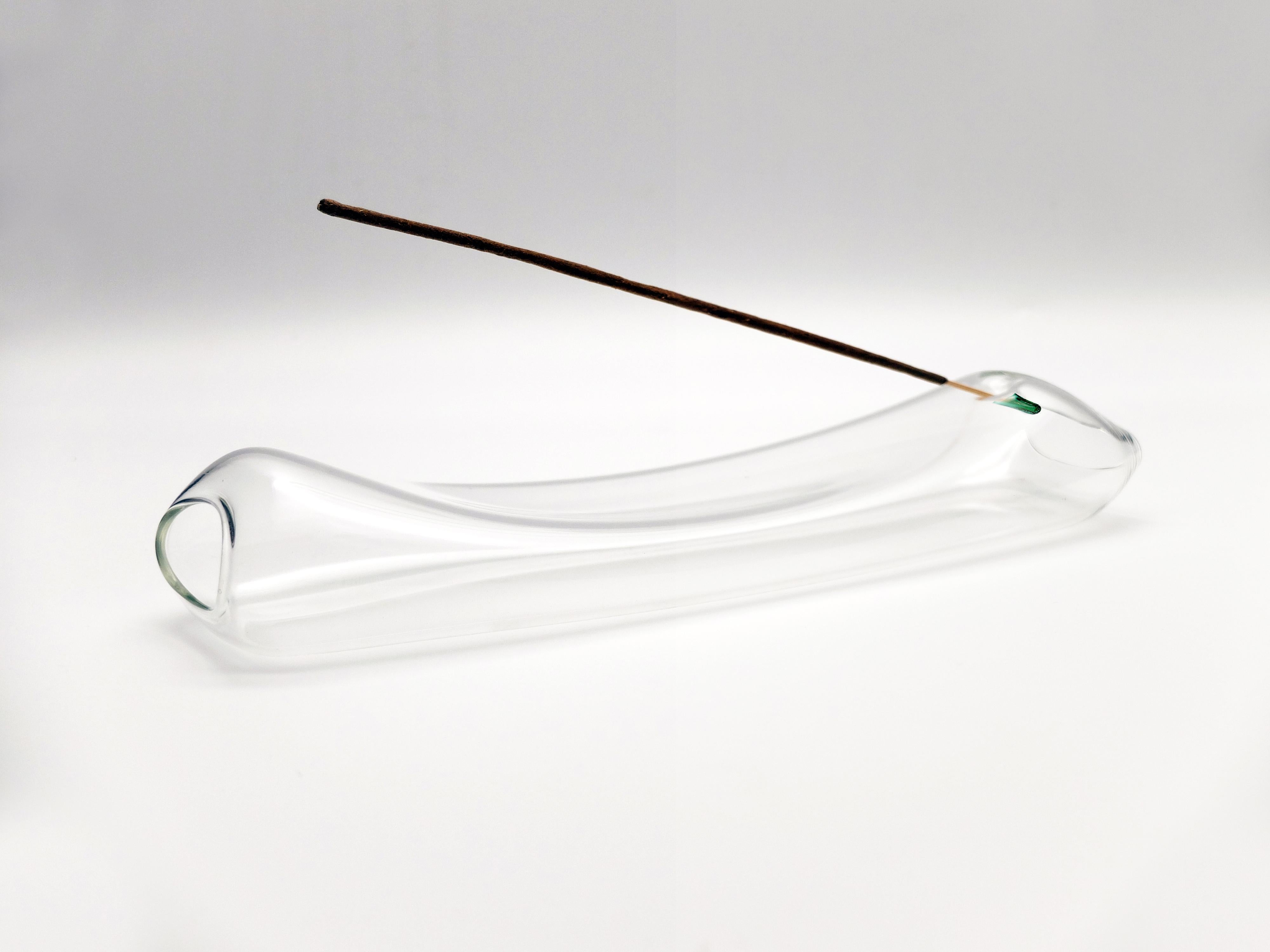 The Smoke incense holder is made of blown borosilicate glass. The design of its shape, soft and light, seems to be defined by the swirls of smoke that rise slowly. The internal void that characterizes it was designed to contain incense sticks. The