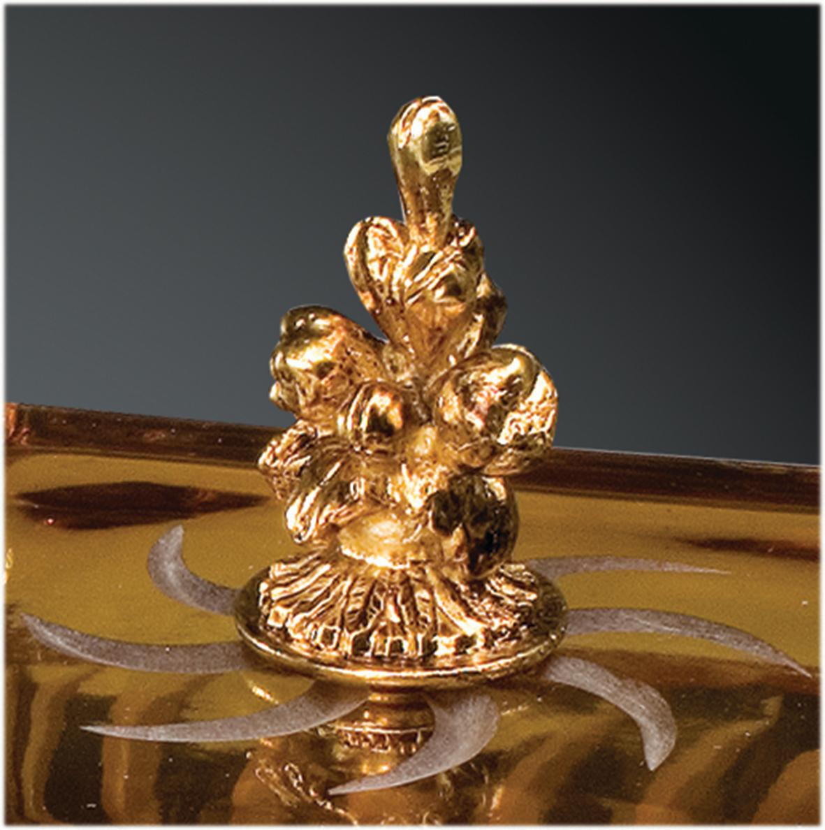 Boîte en cristal ambre avec gravures en taille opaque agrémentées de détails en laiton, réalisée selon la technique artisanale de la cire perdue avec finition en or patiné. Chaque objet est fabriqué à la main et le soin apporté à chaque détail rend