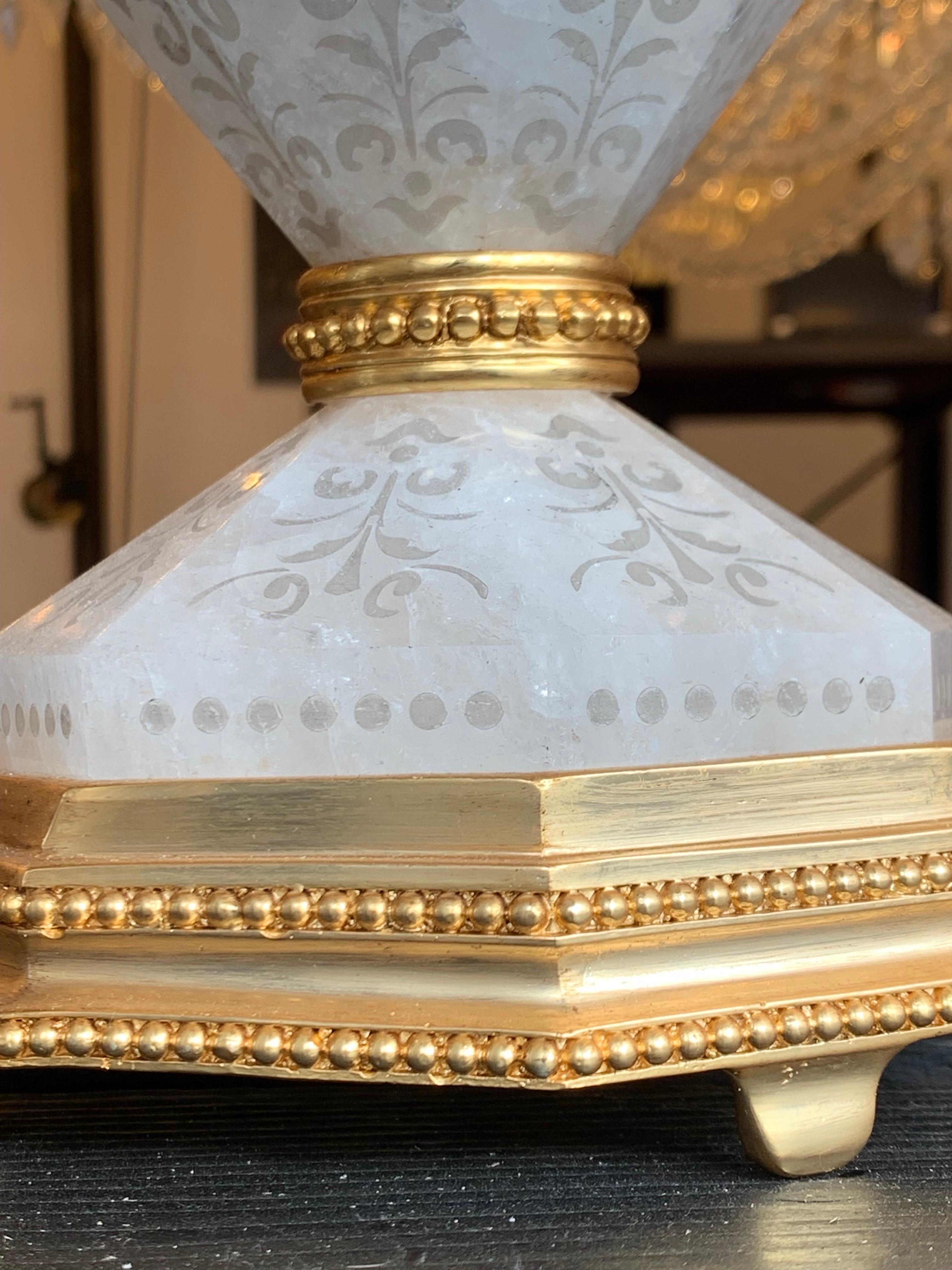 Diese majestätische und elegante Lampe aus 24 Karat vergoldeter Bronze und Bergkristall ist eine Kreation unserer Werkstatt.
Er besteht aus fünf Teilen aus Bergkristall, die sorgfältig mit geätzten Mustern verziert sind. Die Bronzeteile sind fein