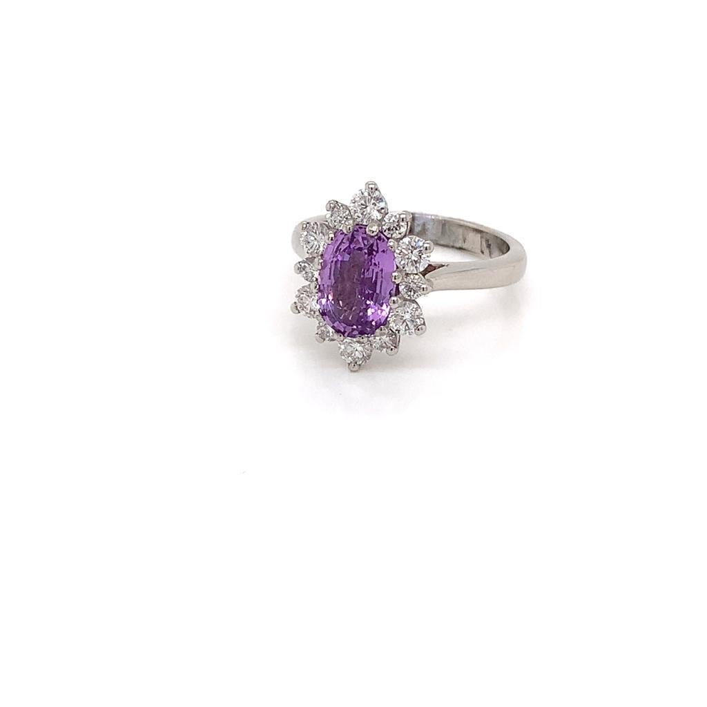 This Enchanting Ring is made of a Precious 2.2 Carat Oval cut Purple Sapphire surrounded by its guard of gleaming Round Brilliant Diamonds weighing 1.1 Carats in total and set in 18K White Gold. The arrangement of these Invaluable gems is like that