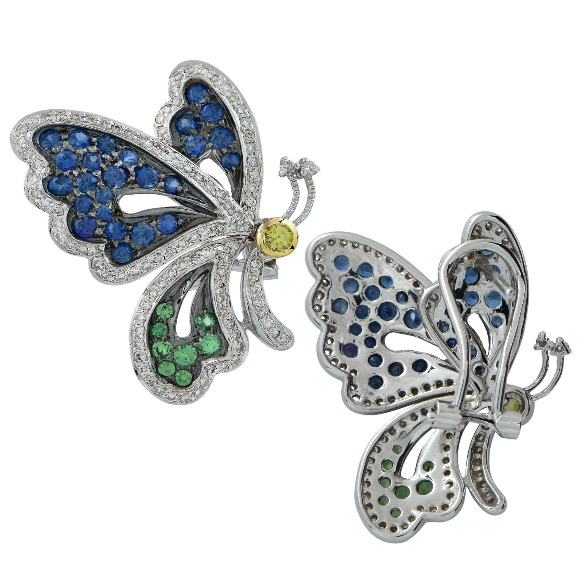 Enchanting 18K White Gold Butterfly Earrings boasting wings encrusted with majestic blue and vibrant green round cut sapphires weighing approximately 1.2cts total, accented with approximately 1ct of round brilliant cut diamonds G-H color SI clarity.
