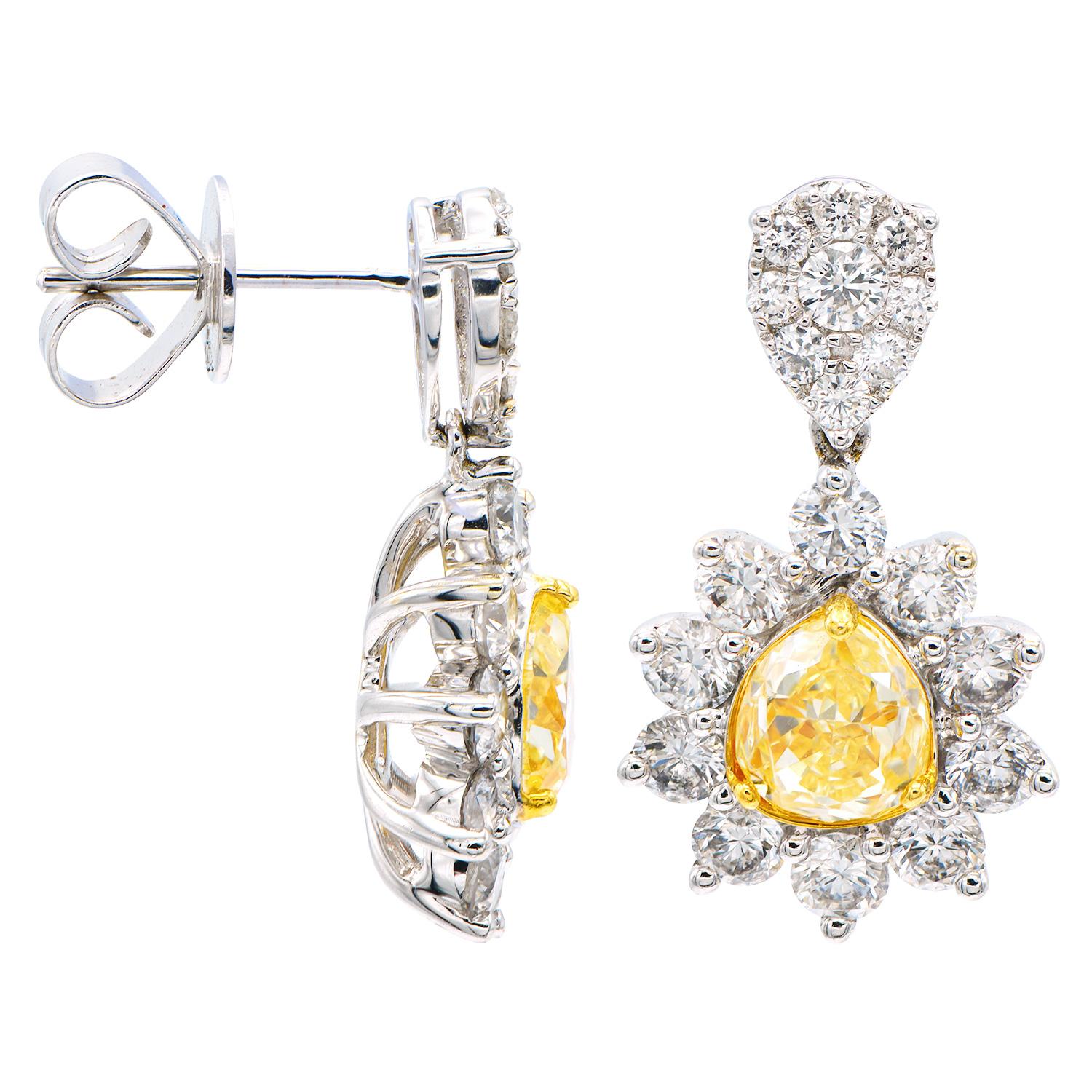 These beautiful earrings contain 2 gorgeous pear cut Yellow Diamonds totaling 2.2 carats which are surrounded by VS2, G color diamonds in a halo around the yellow diamond as well as a diamond cluster on top. There are 38 round diamonds totaling 2.2