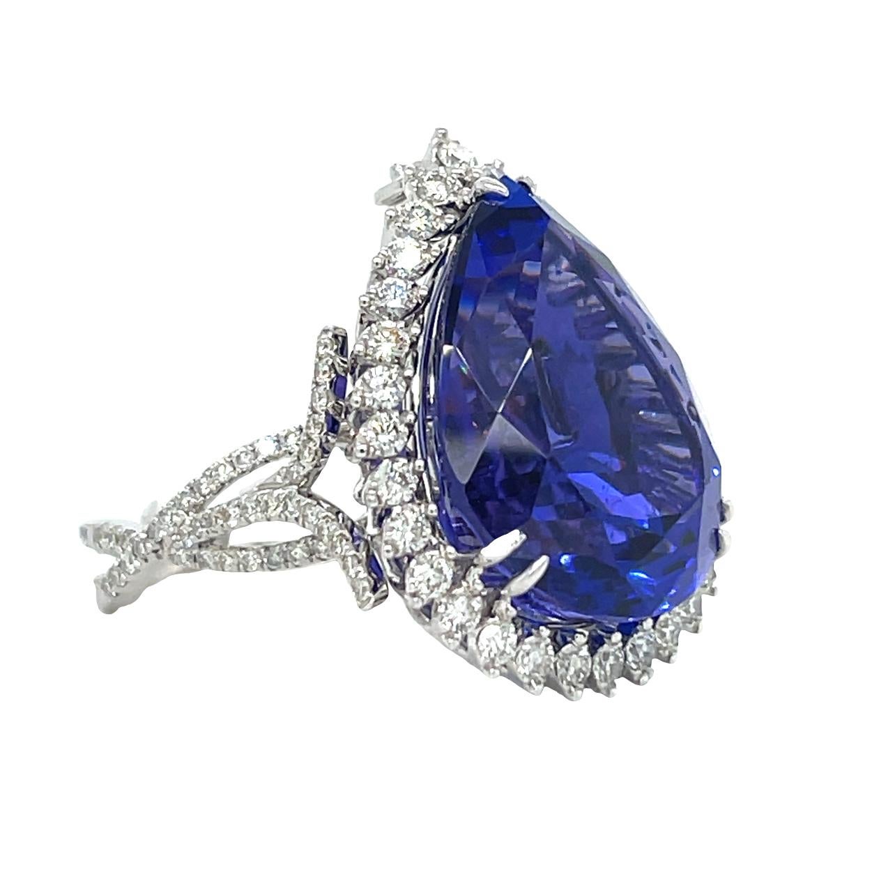 This stunning ring has a deep colored 20x15 mm pear shape AAA quality Tanzanite with 6 prong setting set in 18kt white gold. There top quality brilliant cut diamonds surrounding the center stone and along the fancy shaped shank. This ring comes in a