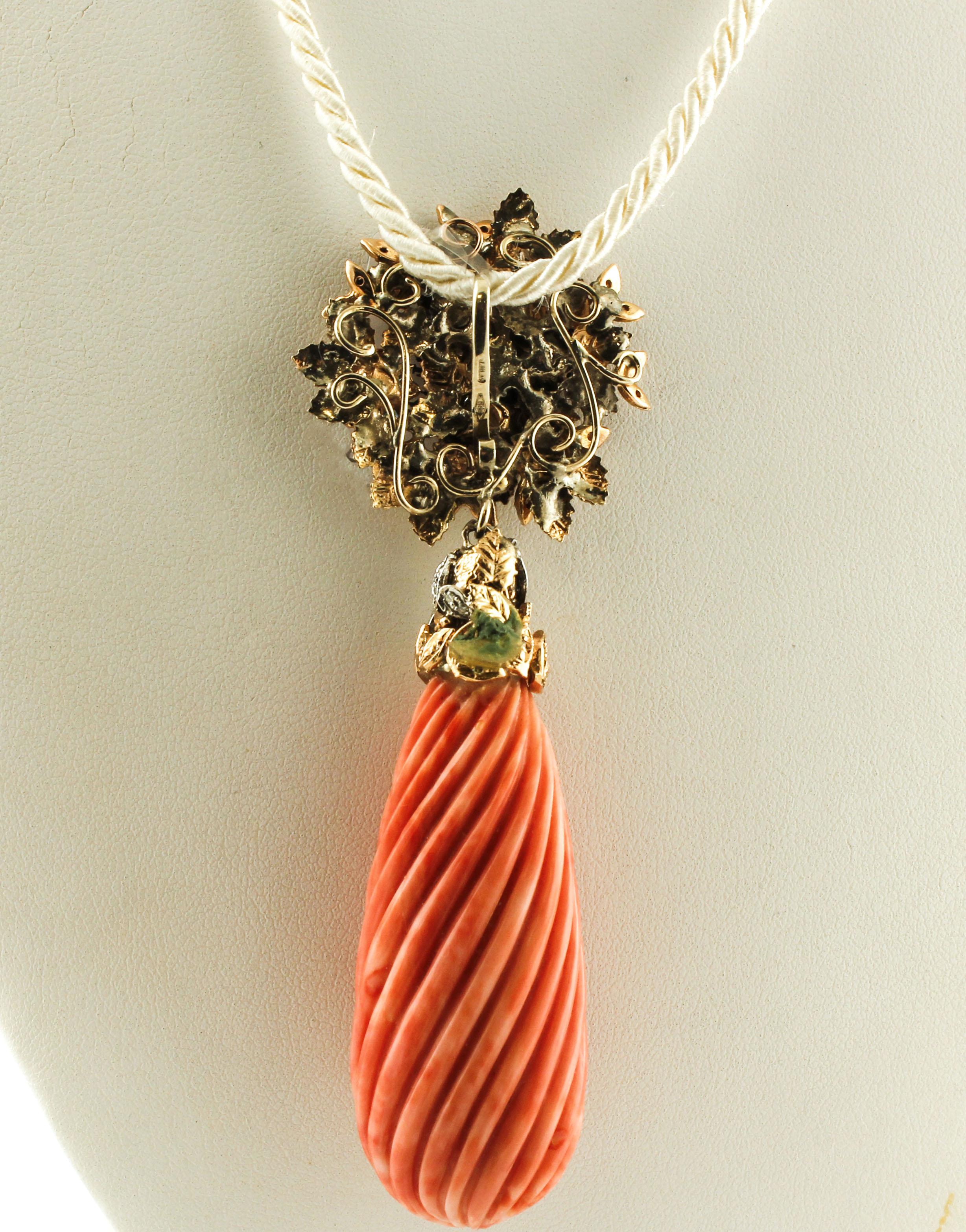 Gorgeous pendant in 14k yellow and white gold, realized with a flowery upper part consisting of yellow and white gold leaves and flowers, enriched with little pearls and diamonds, and a drop-shaped pendant made of elatius coral finely carved. 
This