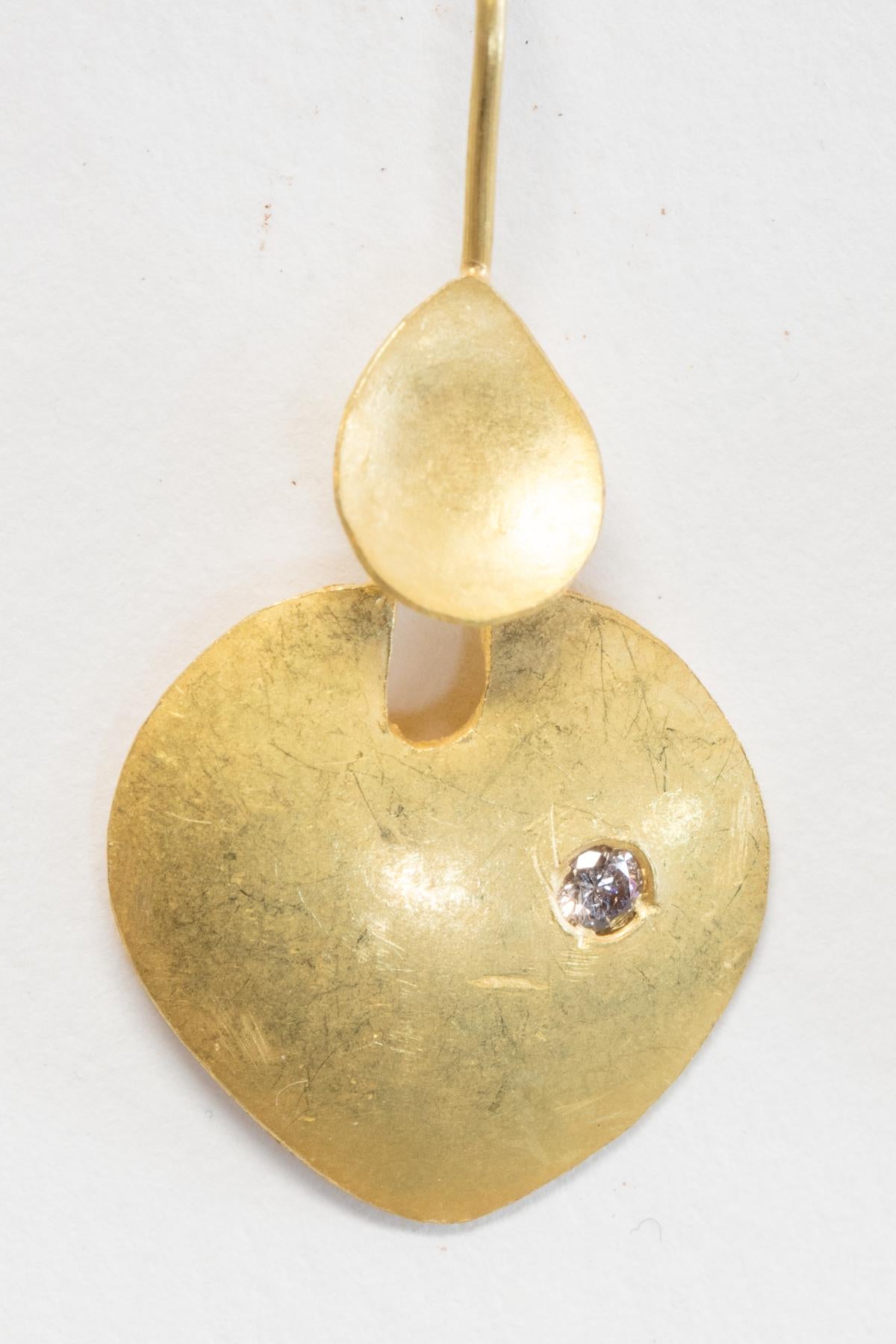 A pair of 22K gold drop earrings in a matte finish with an off-set, faceted diamond inserted into the gold.   On french wire, for pierced ears.