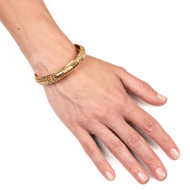 This 22 karat yellow gold bangle features hand carved and engraved details. The inner diameter is approximately 60mm and outer diameter is approximately 65mm. 
Weight: 18 grams