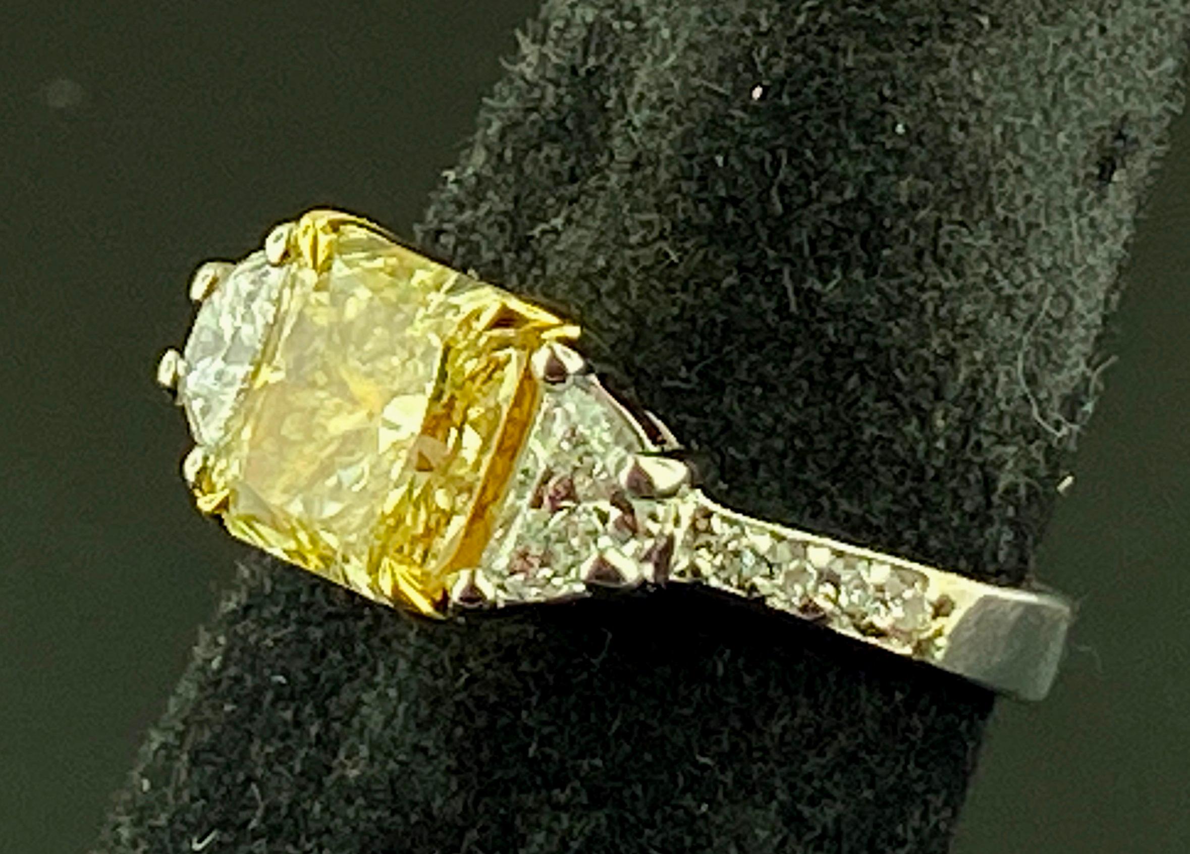 Set in 22 karat Yellow Gold and Platinum is a 1.82 carat Radiant Cut Fancy Yellow Diamond, Clarity VS with two Half-Moon cut diamonds on the side with a total weight of 0.70 carats, Color: H, Clarity: 
VS - SI.  Mounting includes 10 Round Brilliant