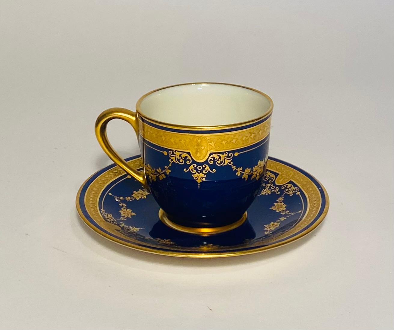 An elegant set of 11 demi cups and 11 saucers for a total of 22 pieces. Made by the American firm of Lenox for the fine Gilded Age Retailer Marshall Fields of Chicago. This set features raised gilt floral swags on a rich cobalt blue ground. We do