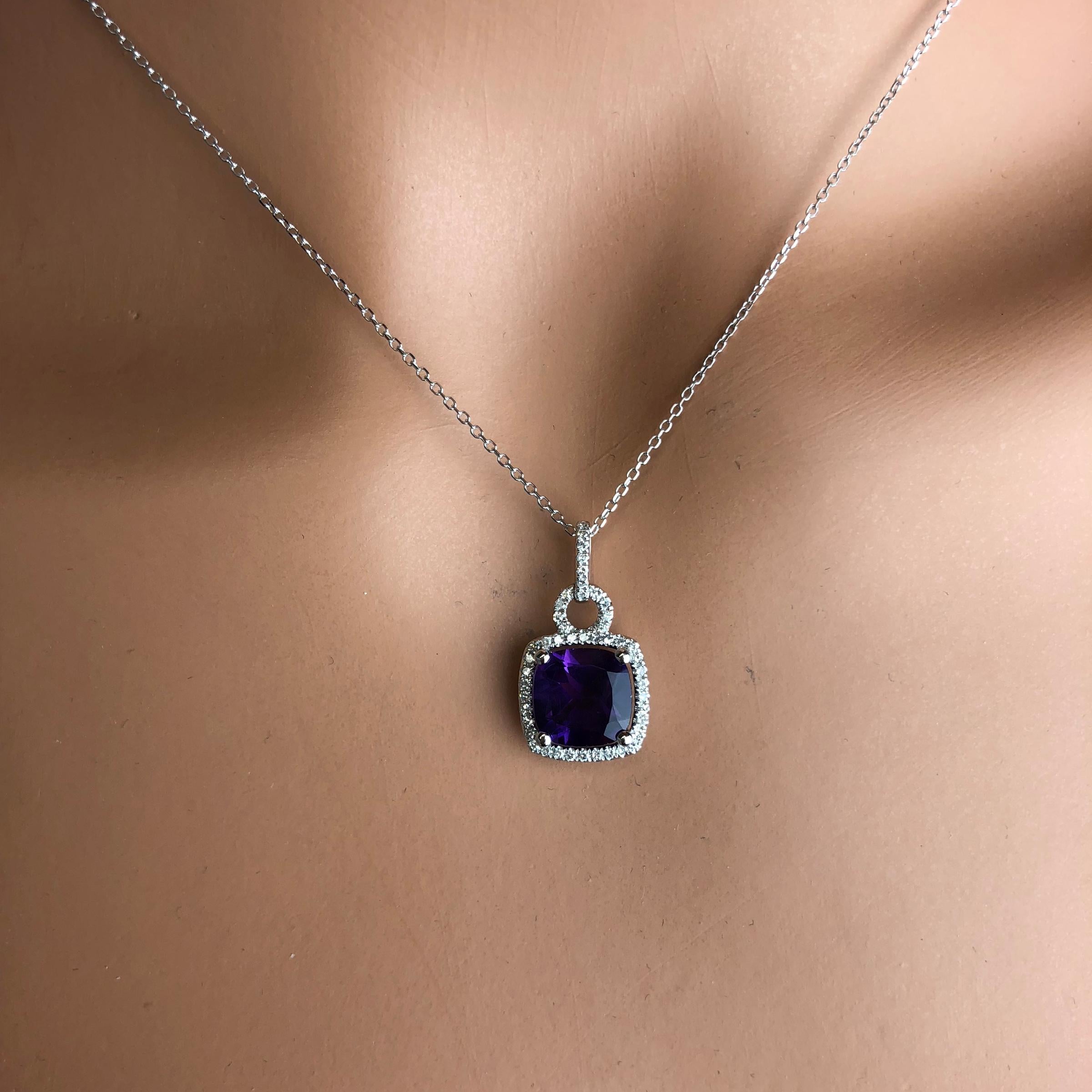 (DiamondTown) This lovely halo pendant features 2.20 carats cushion cut fine amethyst, surrounded by a halo of round white diamonds. Additional diamonds decorate the bail.

Center: 2.20 Carat Fine Amethyst
Diamond Halo: 47 round diamonds total 0.18