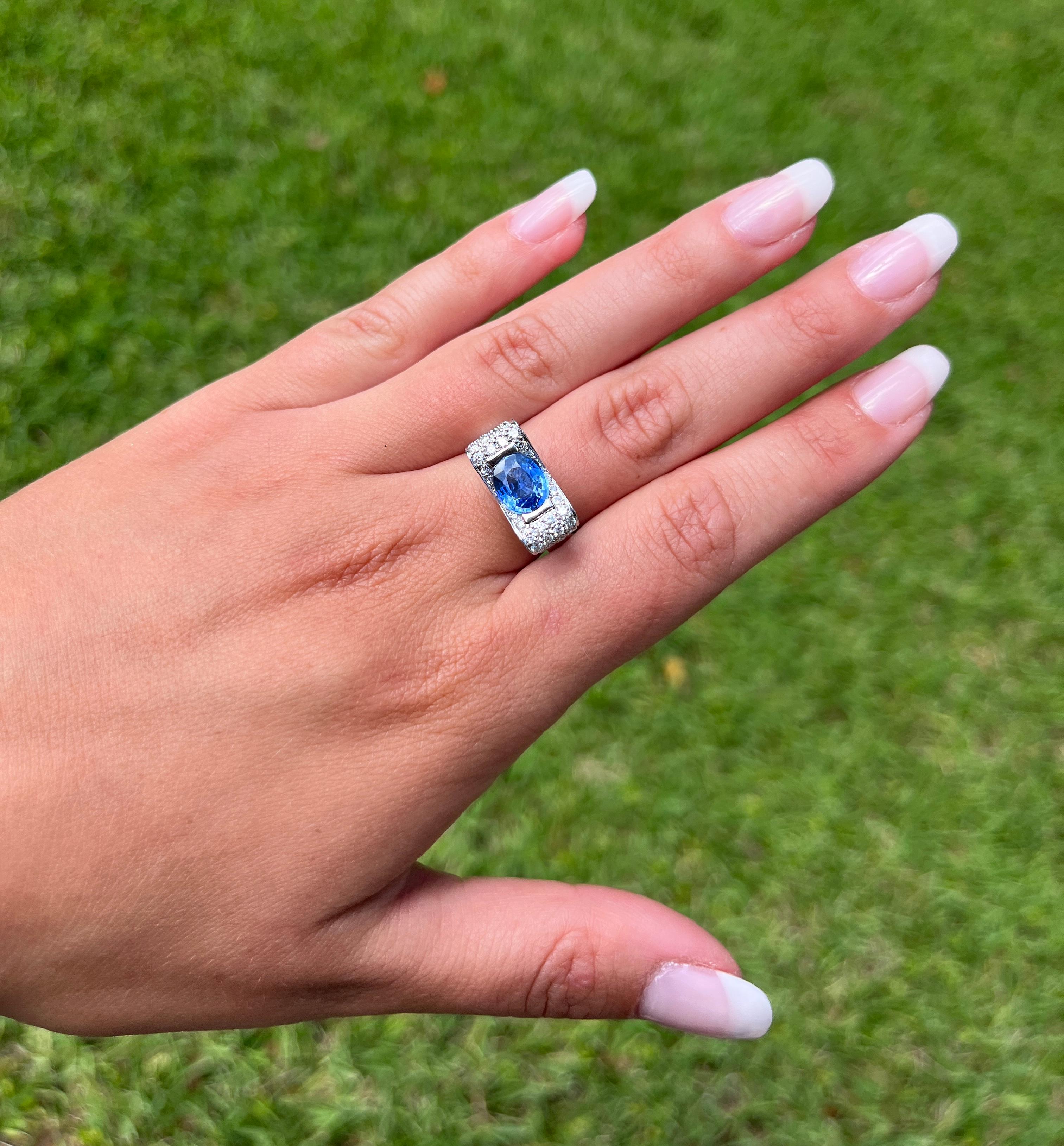 Natural Tanzanite and Diamond Bow Style Ring, featuring a captivating 2.20 carat Blue dominant Tanzanite, half bezel-set, and adorned with 1.01 CTTW in round cut diamond side stones. Crafted in 18K white gold, this ring beautifully combines the