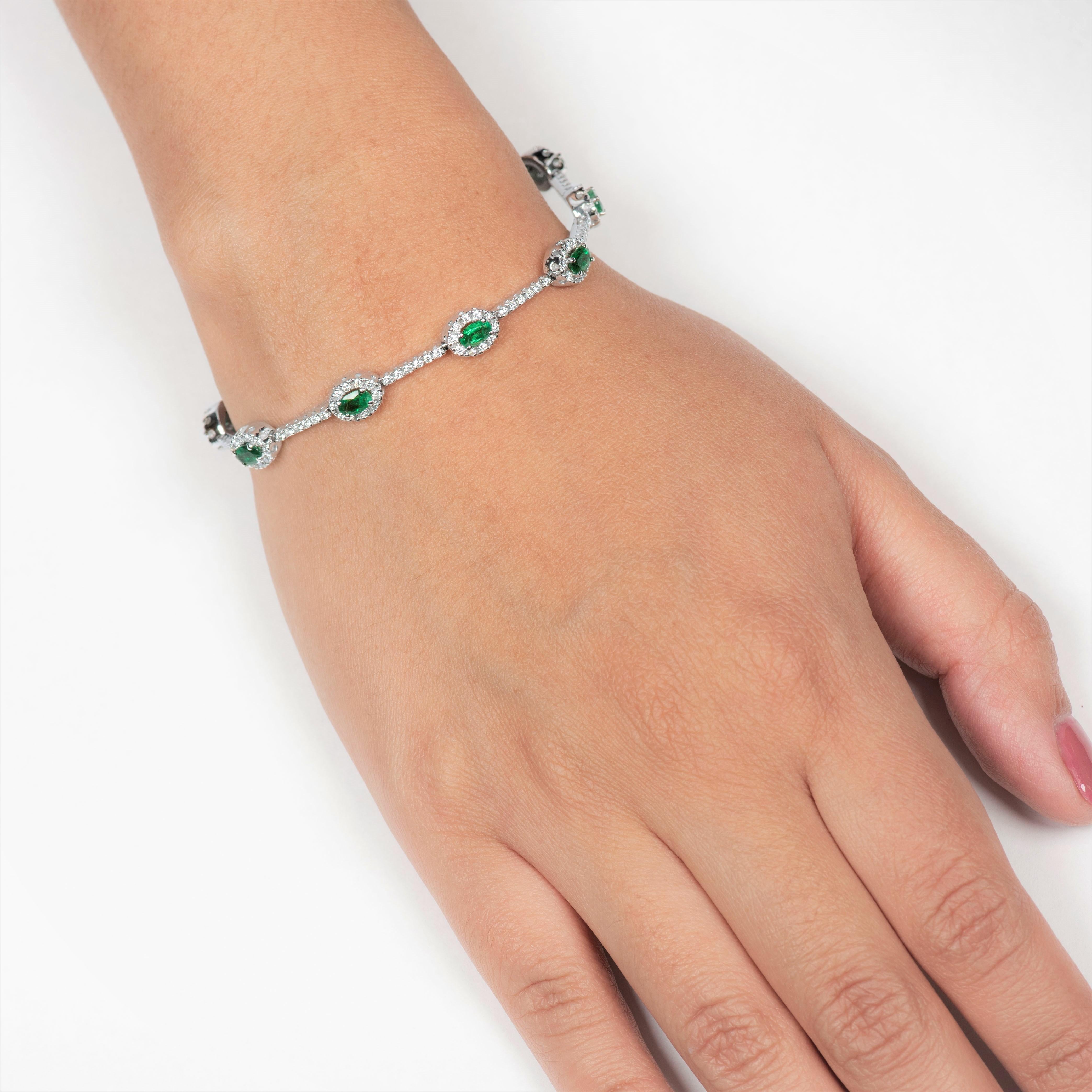 This gorgeous 2.20 carats emerald bracelet is styled with 10 perfectly matched oval cut emeralds that are formally surrounded by a halo of  1.37 carats of round brilliant cut diamonds (180 diamonds). The bracelet measures at a length of 7 inches and