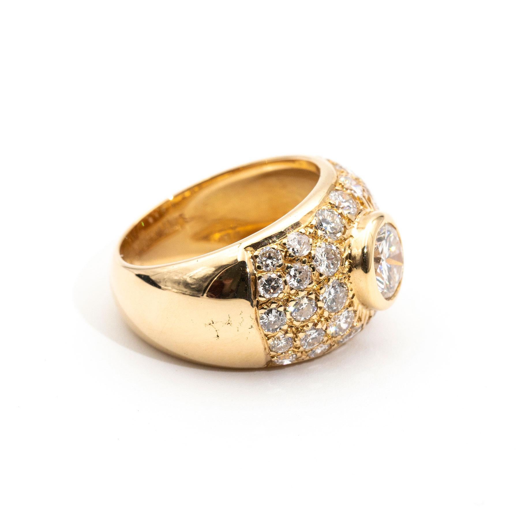Masterfully forged in 18 carat yellow gold, this captivating vintage engagement ring is a sight to behold. A striking centrepiece 0.88 carat rub over round brilliant diamond rests in a frontal dome encrusted with a further 1.32 carats of shimmering