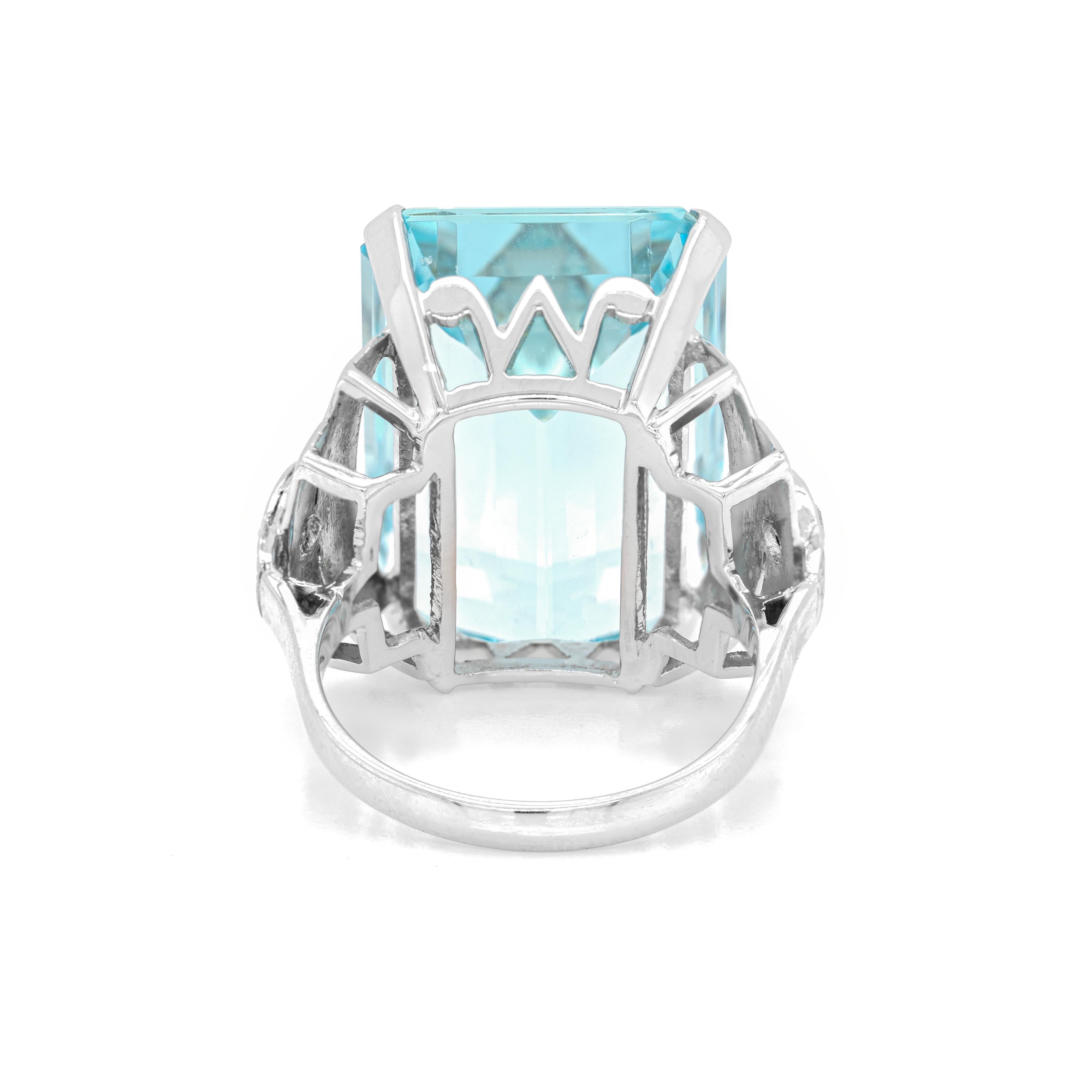This spectacular 18 carat white gold cocktail ring is beautifully set with an emerald cut aquamarine weighing an impressive 22.00 carats mounted in a four claw, open back setting. An open work gallery and two eight cut diamonds weighing