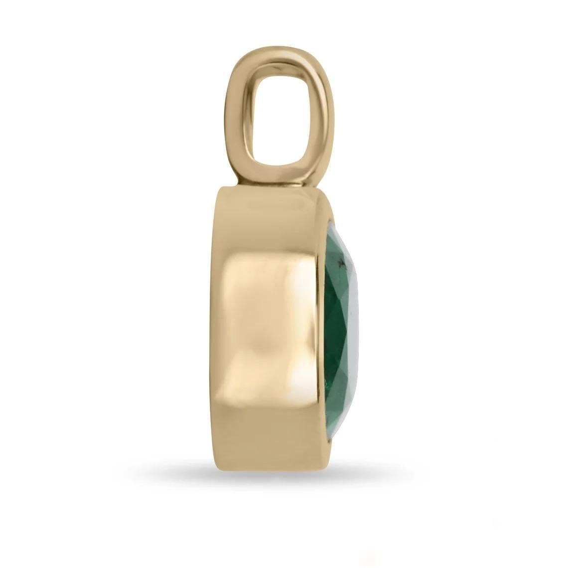 This beautiful solitaire pendant showcases a stunning dark green oval-cut emerald that is expertly bezel set in 14k gold. The simplicity of the design highlights the natural beauty and elegance of the emerald, making it a timeless and sophisticated