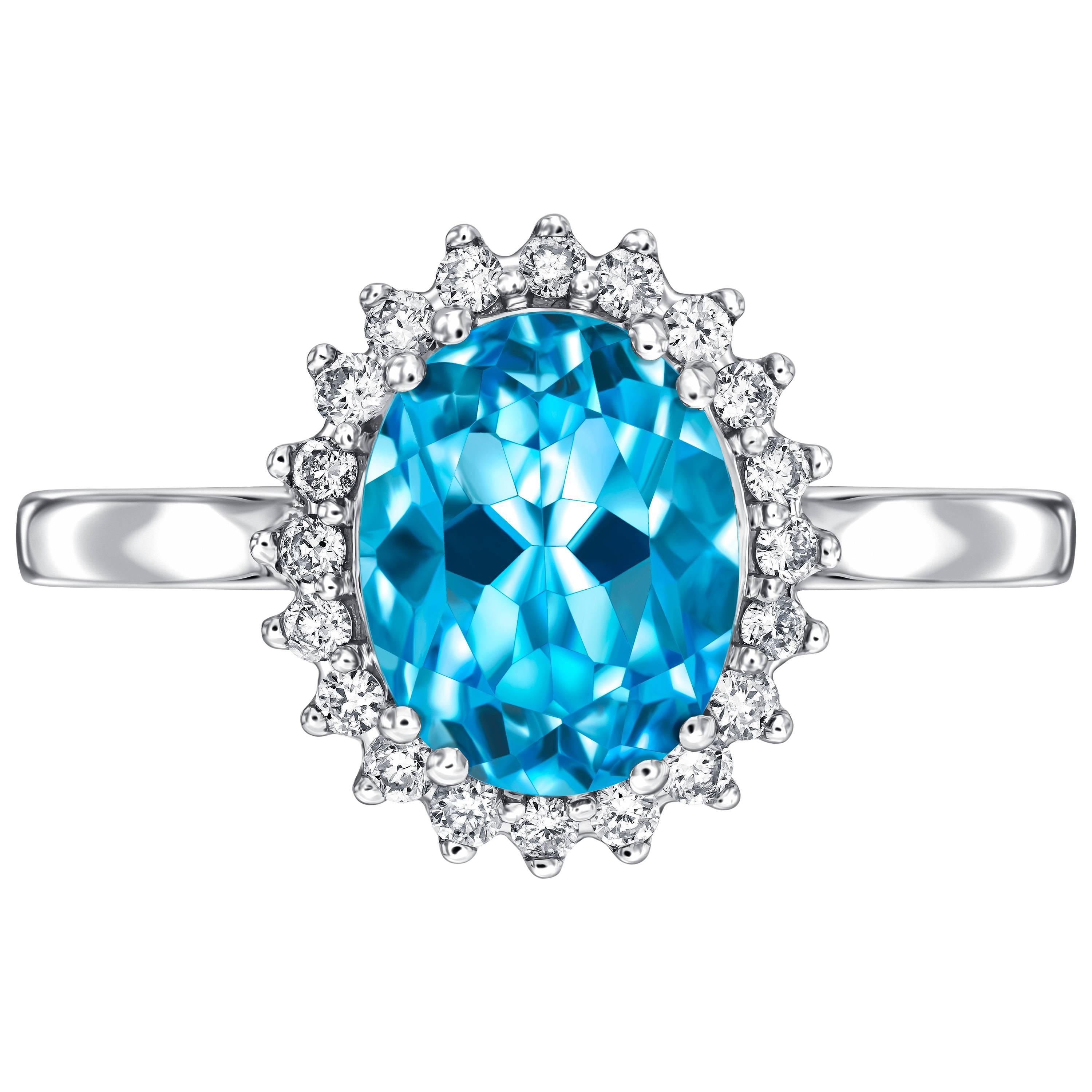 Vintage 18k white gold ring with 2.20ct blue topaz centerpiece and a cluster of 0.20ct H-SI diamonds. Each diamond from the halo is set with a triple claw for a spikey edged look reminiscent of a more floral style. This ring has a total weight of