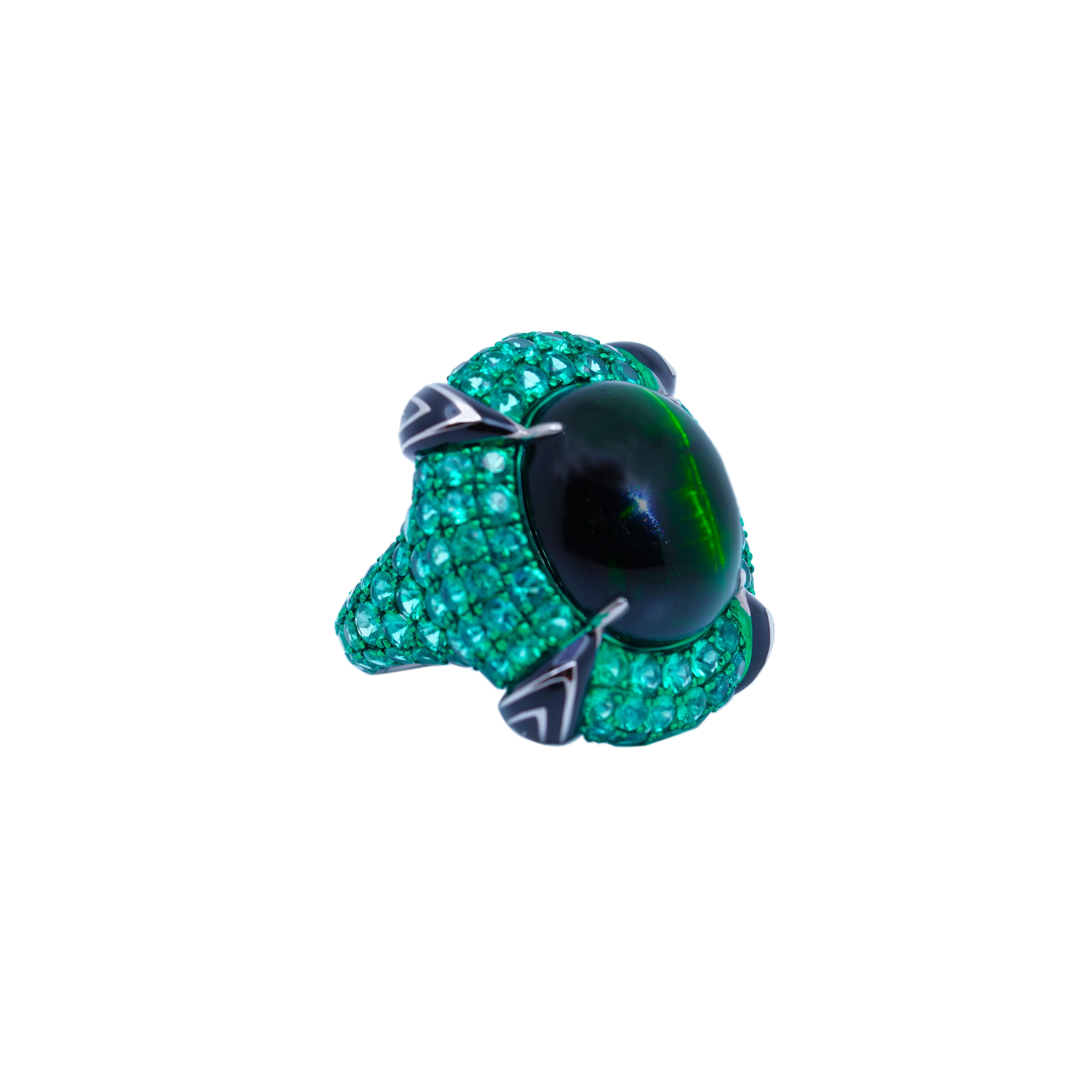 The Artemis' Pupil Ring from The Vision of God Collection by Austy Lee is a truly magnificent and timeless piece of jewelry. At the heart of this captivating design is a mesmerizing 22.1-carat cabochon Cat's Eye Green Tourmaline, a rare and
